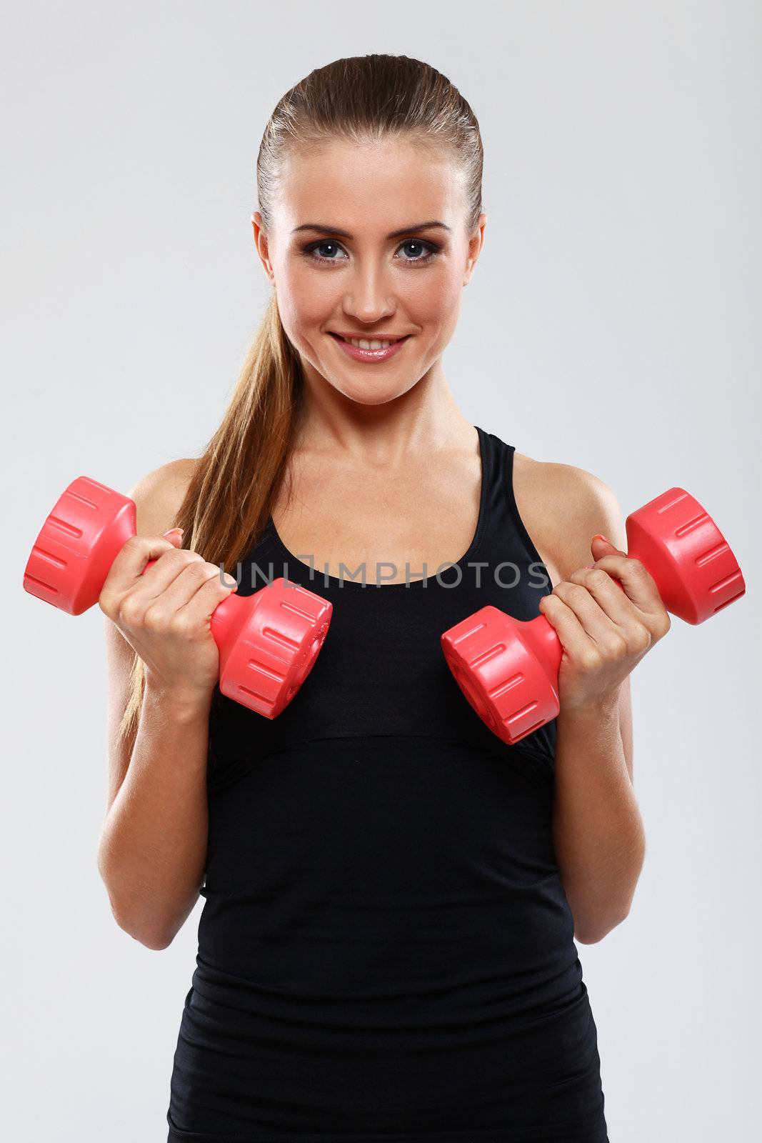 Beautiful brunette working out with dumbbells over gray background