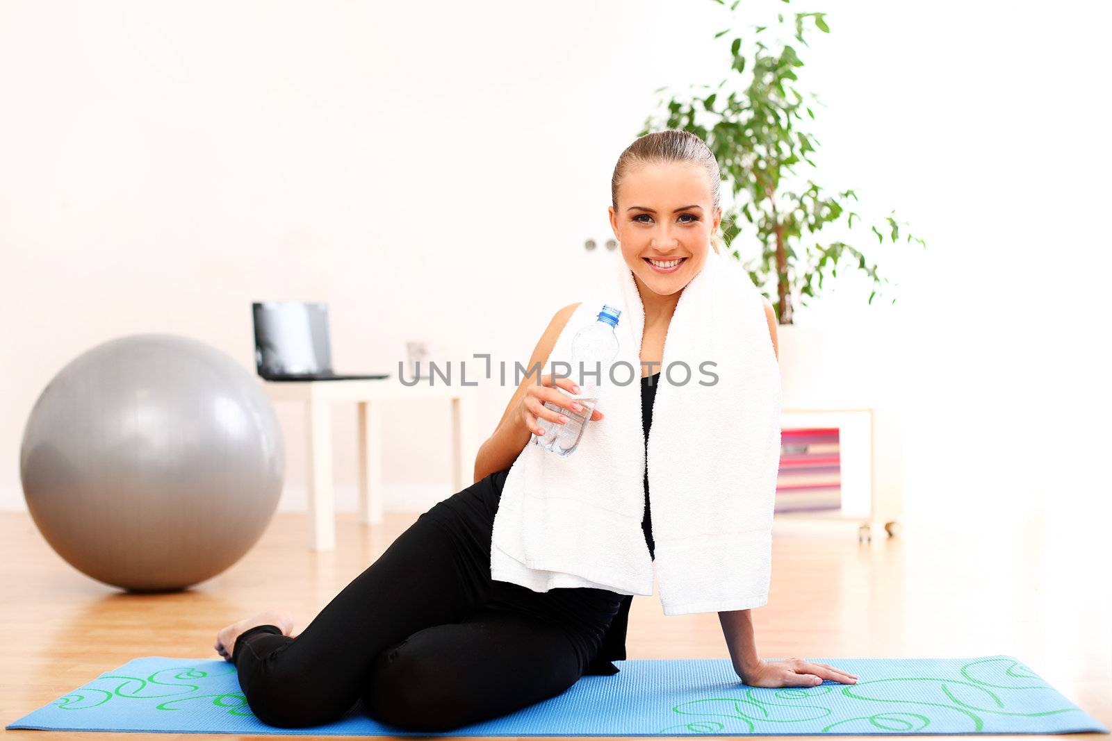 Closeup of girl with towel drinking water after fitness training at home