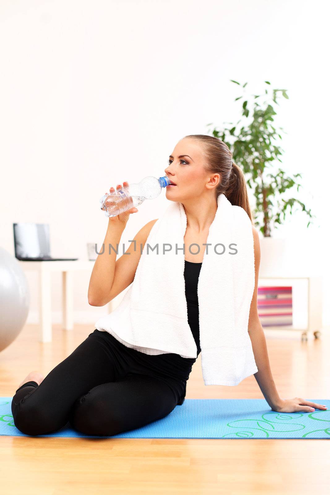 Closeup of girl with towel drinking water after fitness training at home