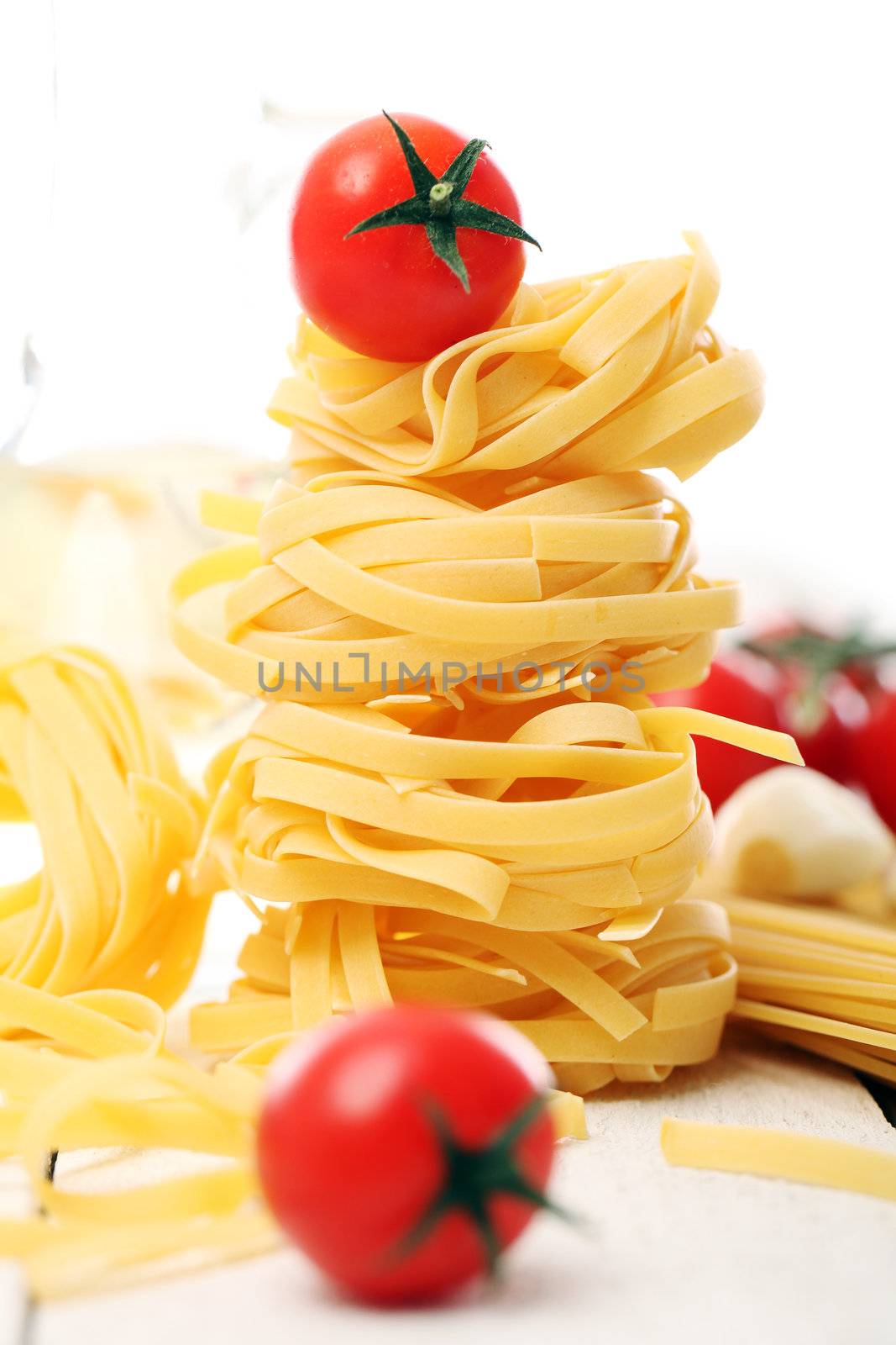 Italian pasta and cherry tomato on wooden surface isolated on a white background