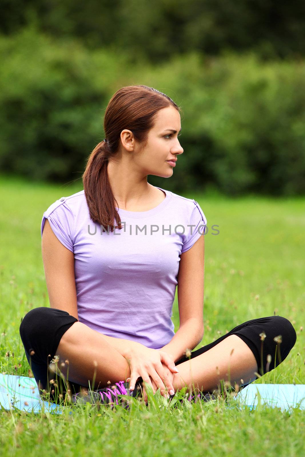 Young and beautiful woman doing her yoga workout on the park`s lawn