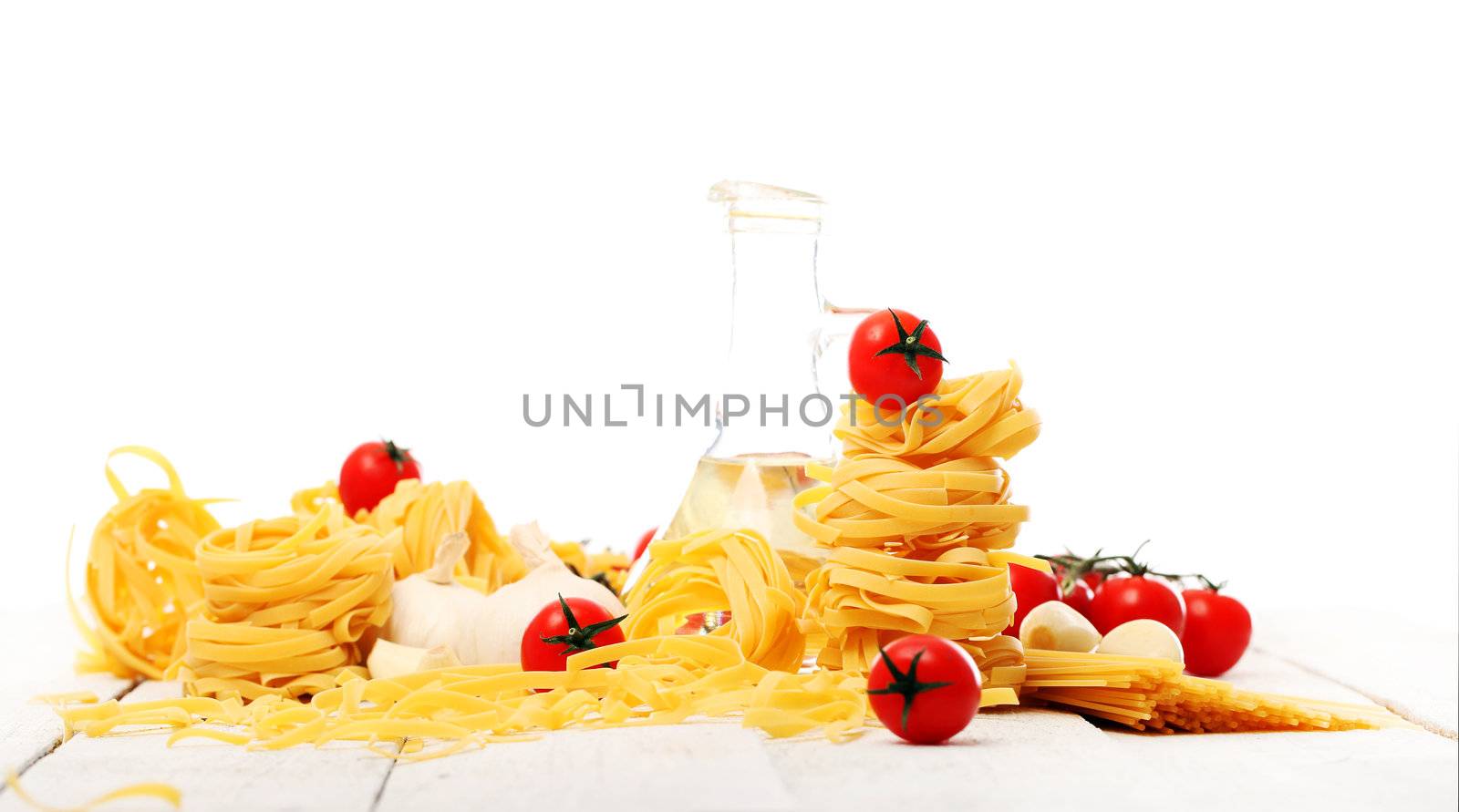 Italian pasta, cherry tomato and bottle of water on wooden surface isolated on a white background