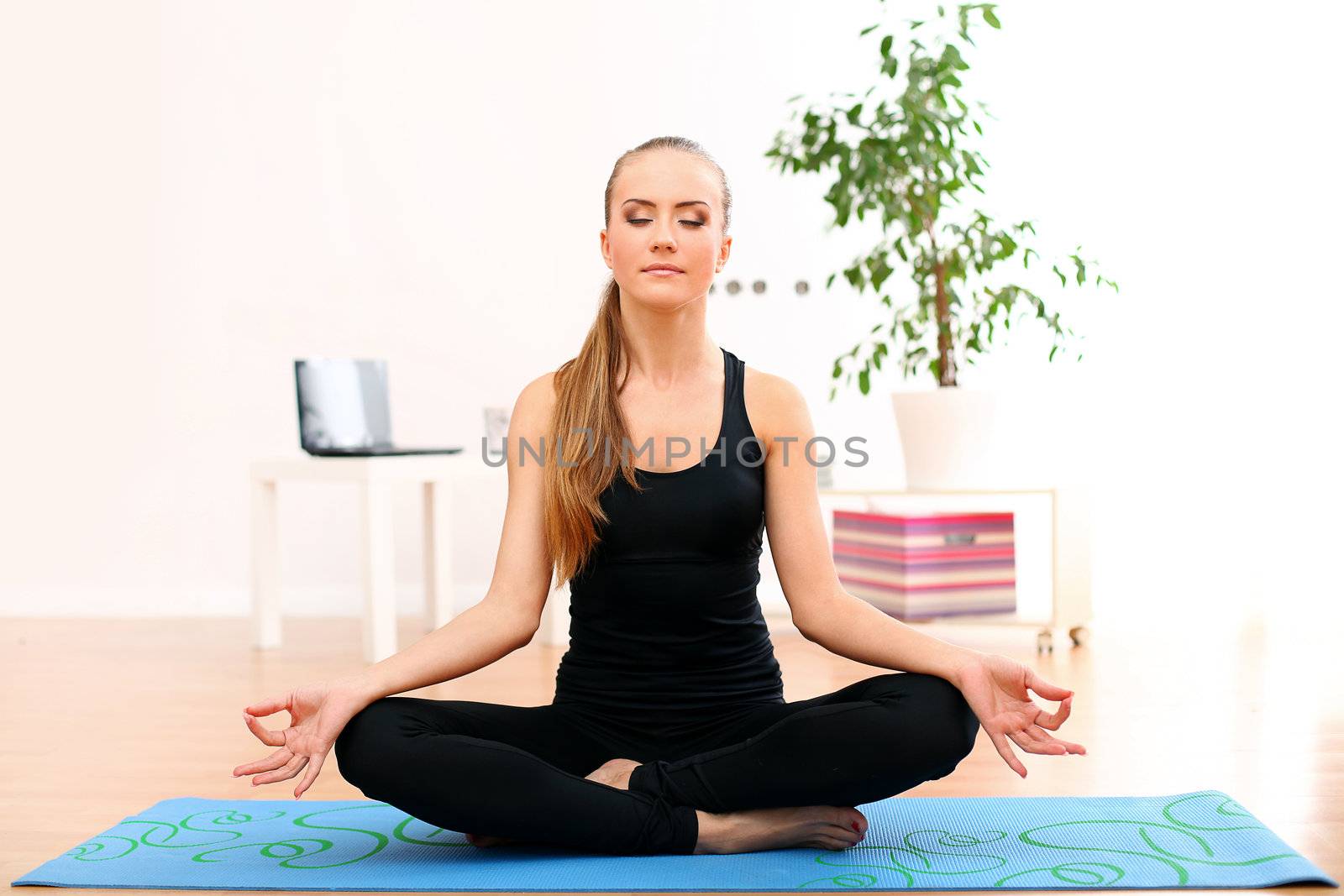 Young and beautiful woman meditate at home on blue mat