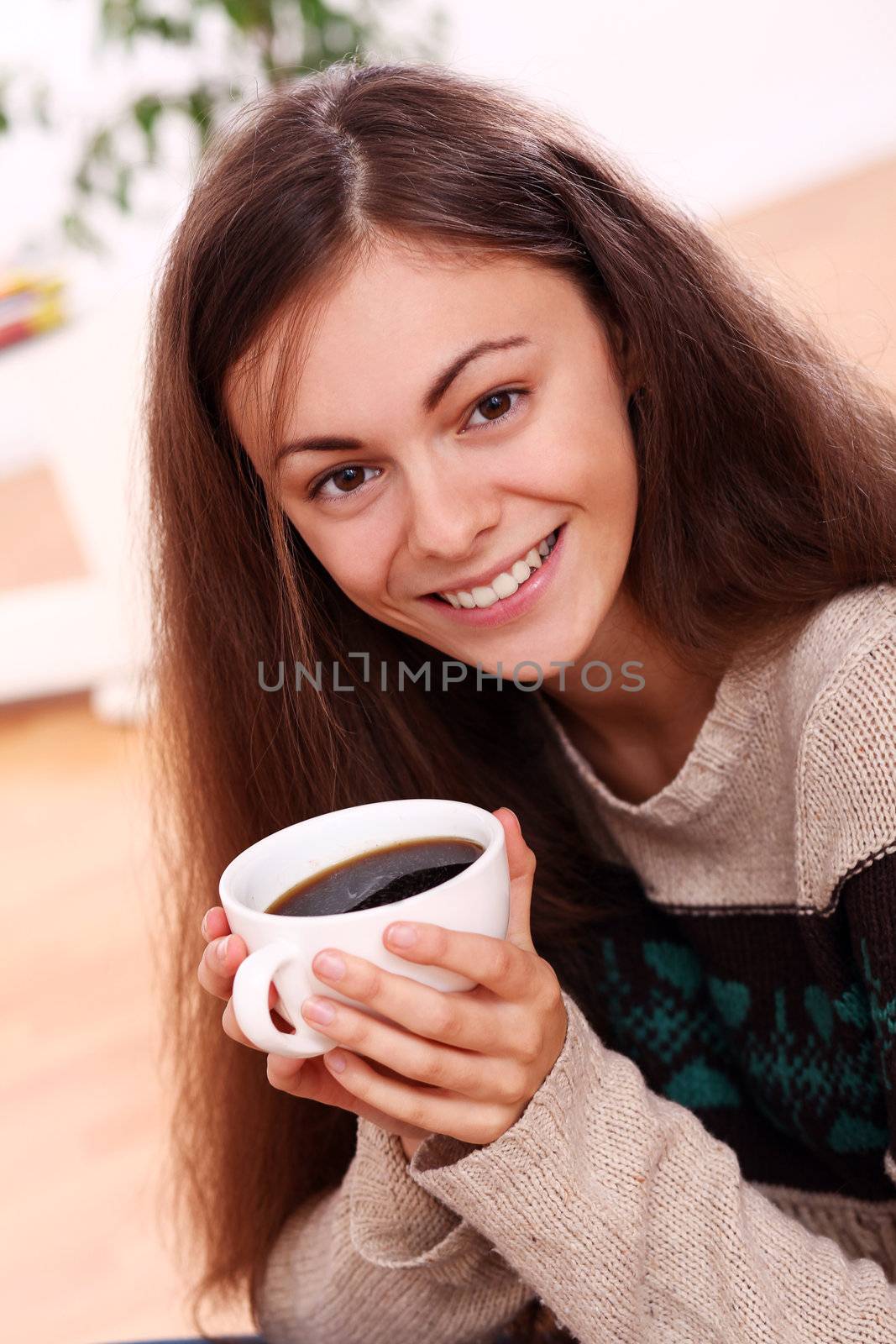 Close up of cute and attractive young woman have a warm from cup of tea at home