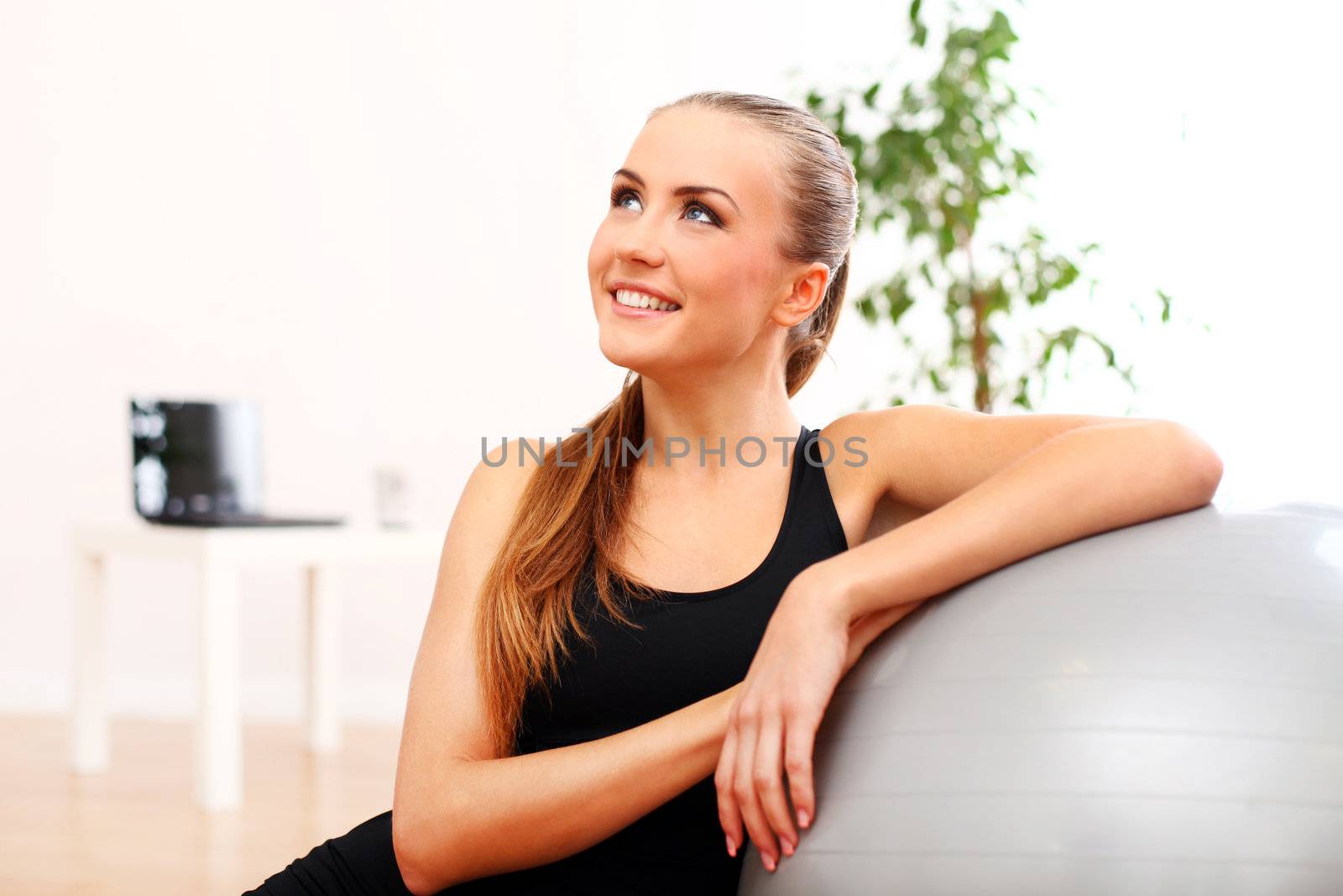 Close up of happy and beautiful woman with fitness ball at home