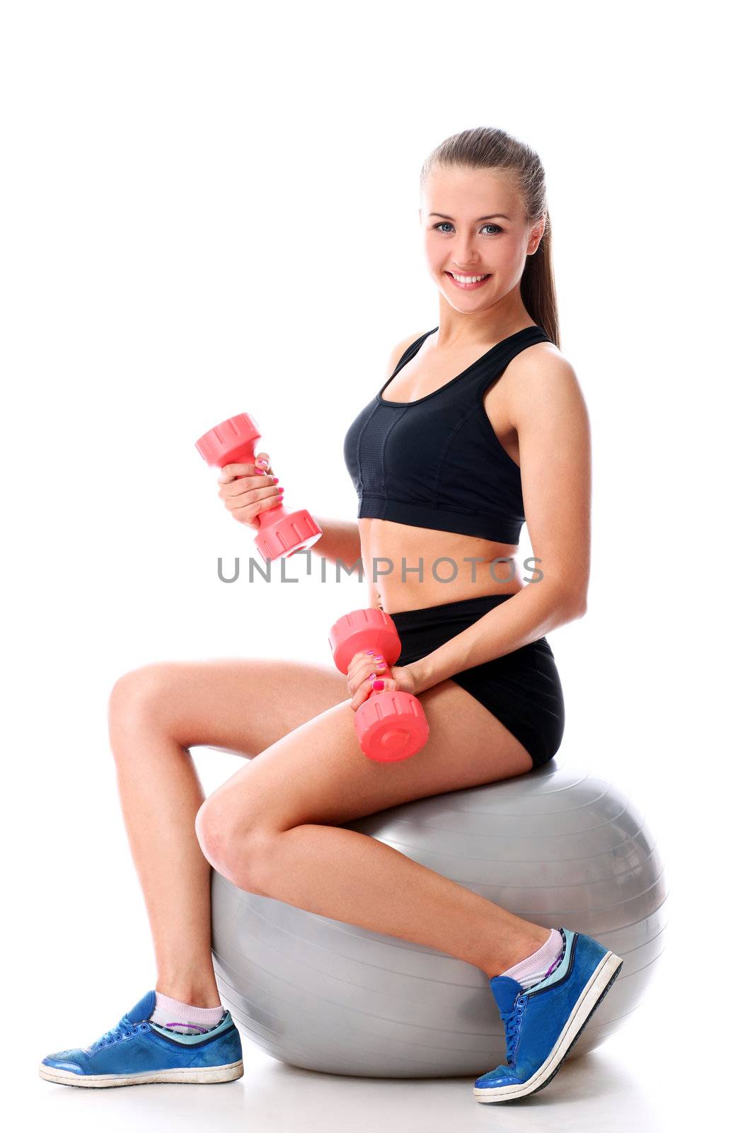 Young woman doing exercise with dumbells on a ball by rufatjumali