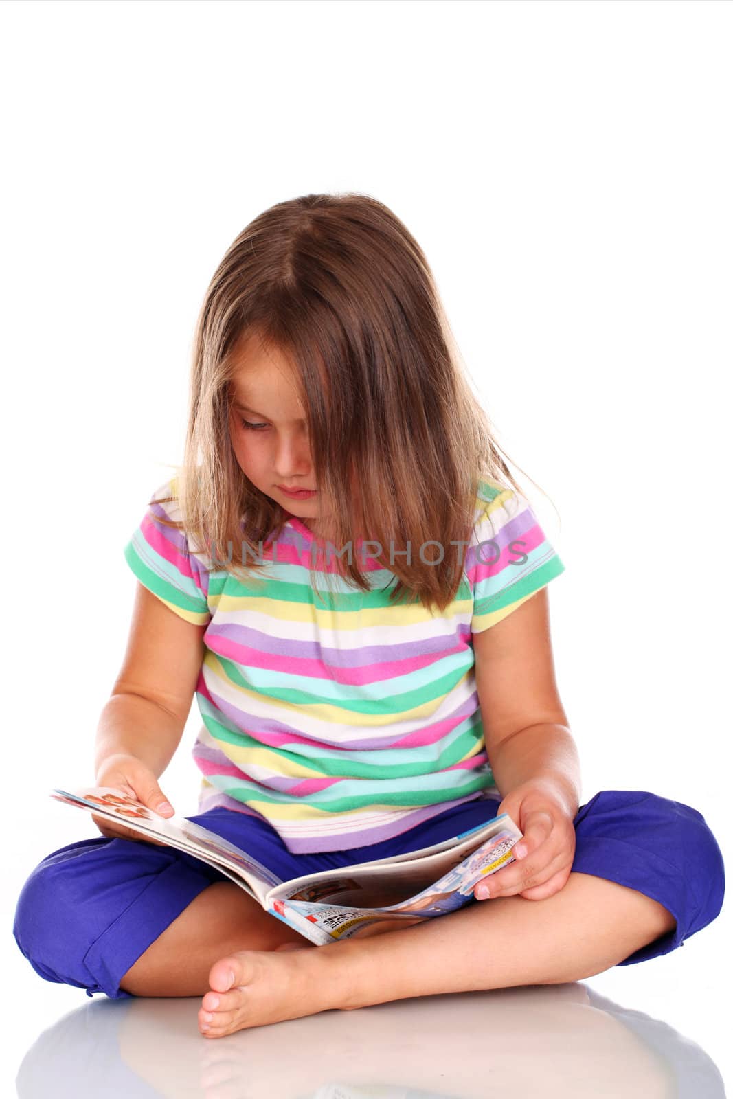 Cute little girl reading book isolated on white