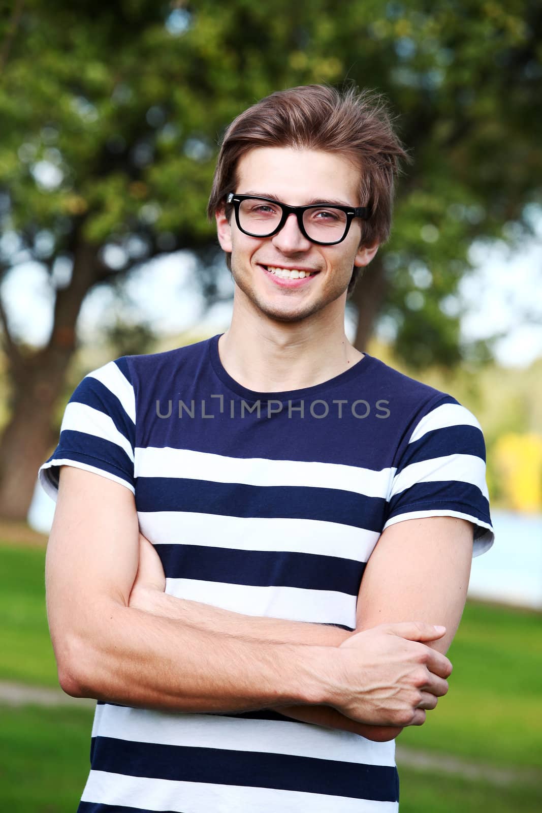 Portrait of young and smiling cute man with glasses in park