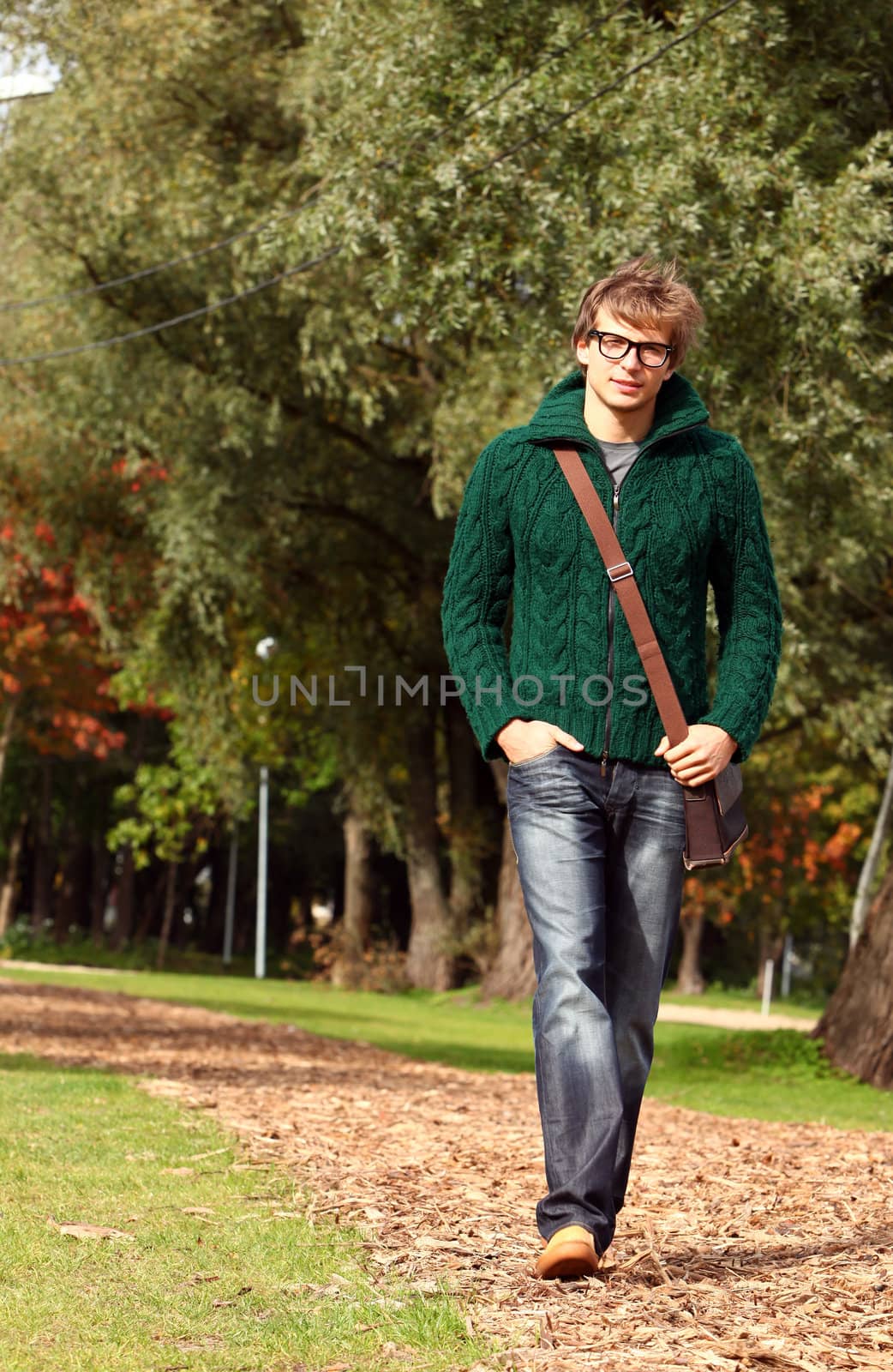 Cute and smart guy walking at cold autumn day in sunny park