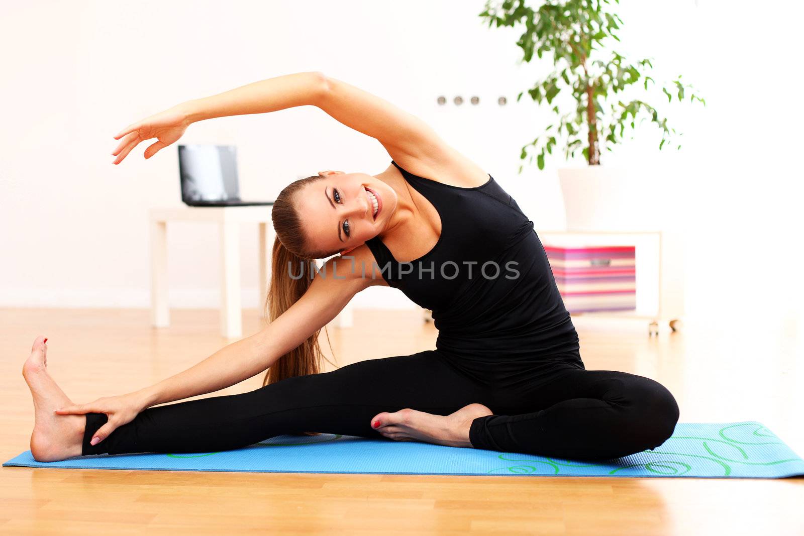 Happy and beautiful woman do yoga exercises at home on blue mat