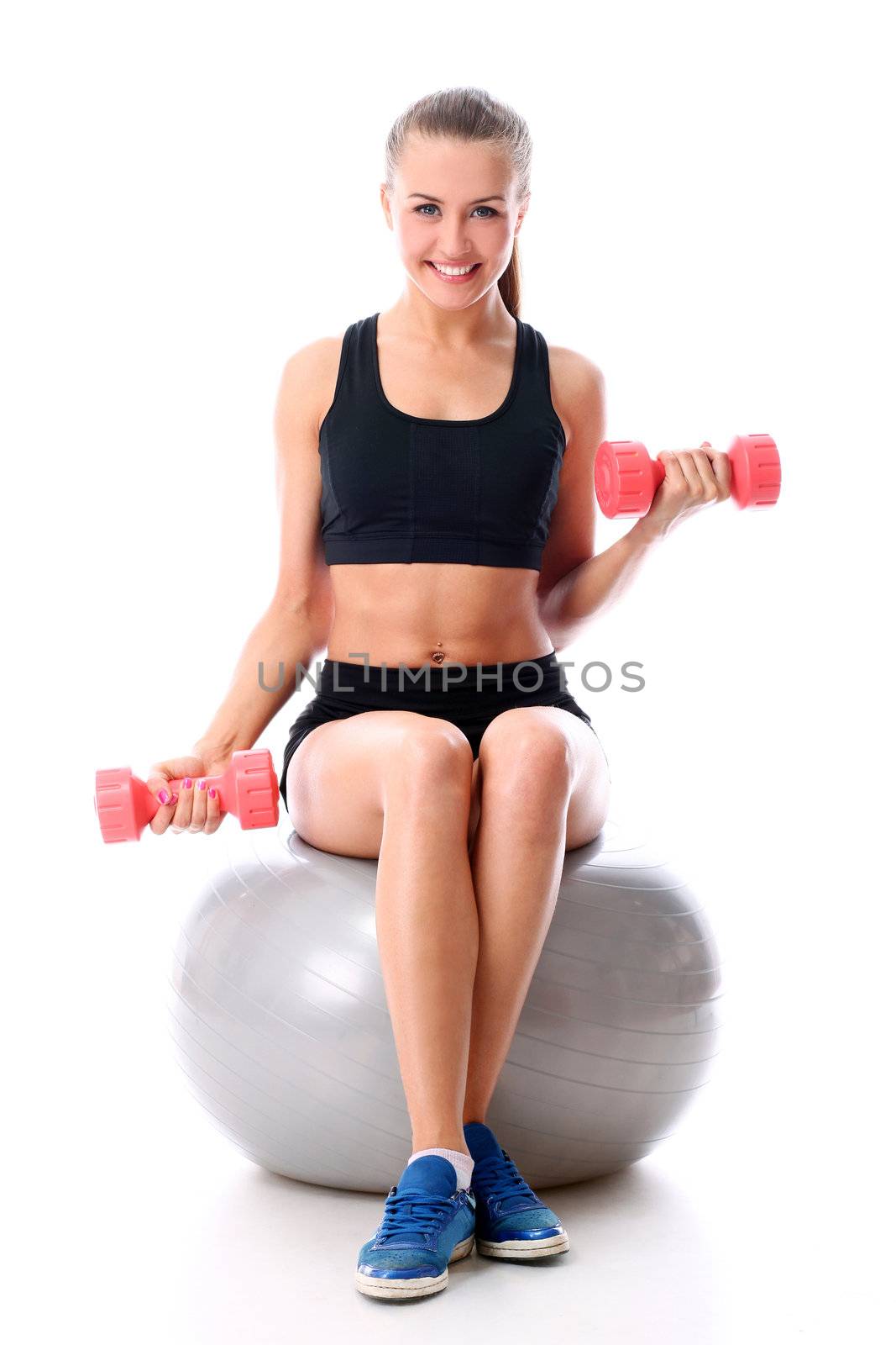 Young woman doing exercise with dumbells on a ball by rufatjumali