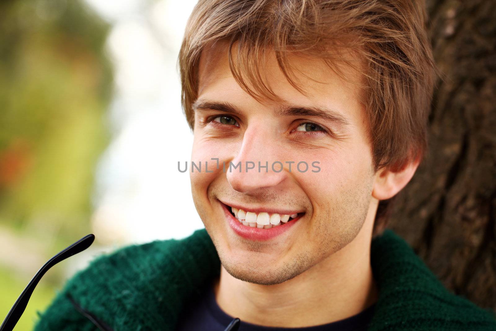 Potrait of young handsome guy at cold autumn day in the park