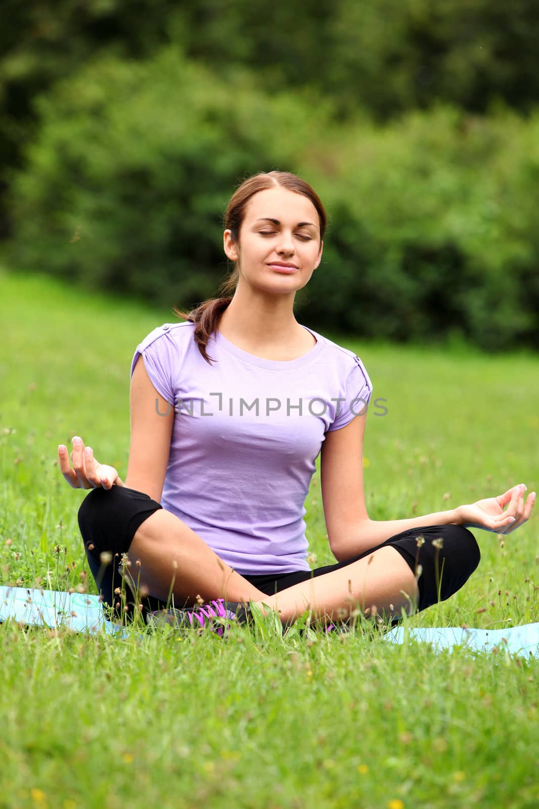 Young and beautiful woman doing her yoga workout on the park`s lawn