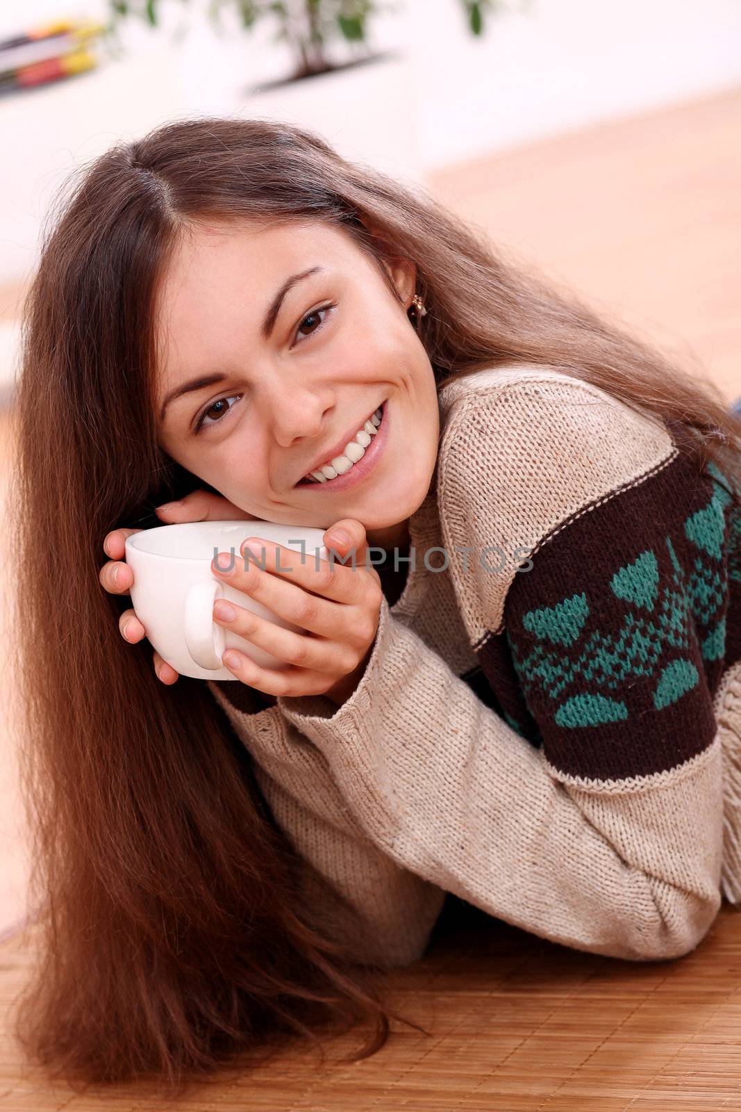 Close up of cute and attractive young woman have a warm from cup of tea at home