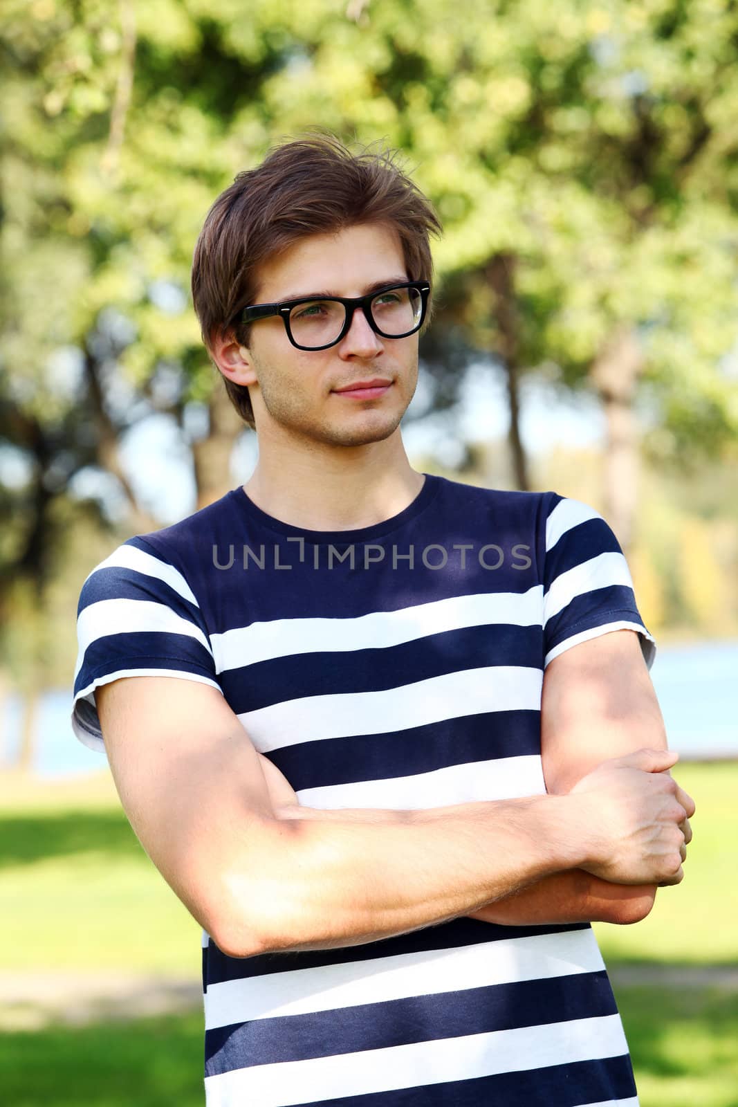 Portrait of young and smiling cute man with glasses in park