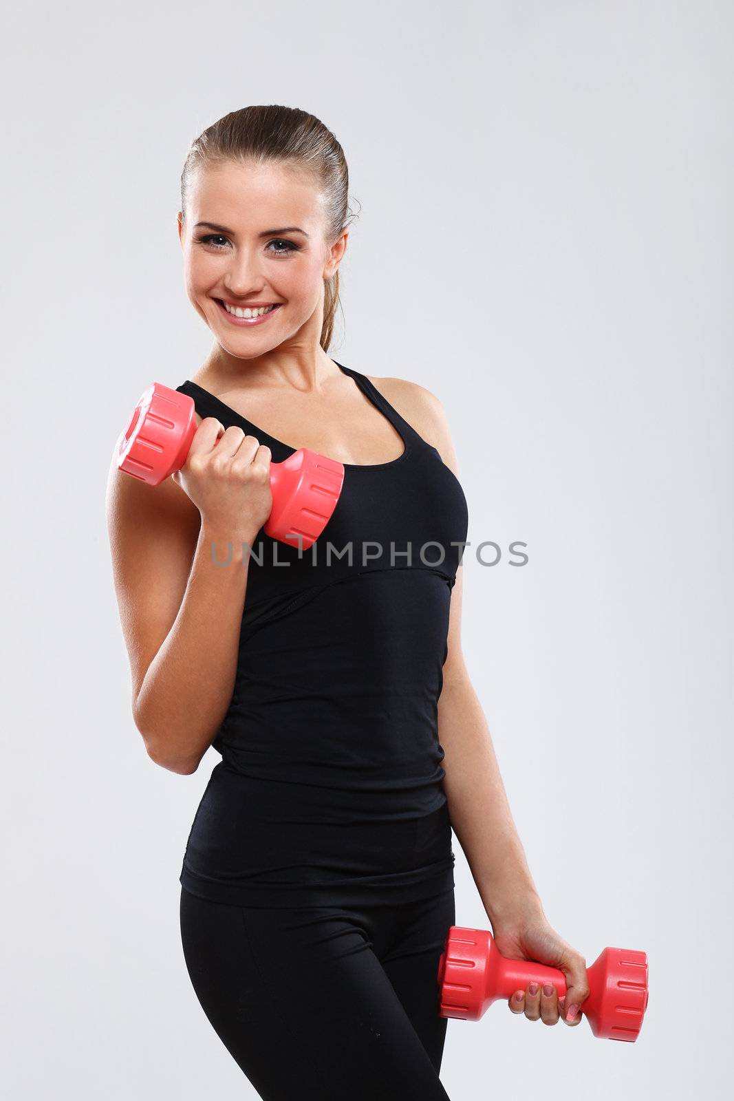 Beautiful brunette working out with dumbbells over gray background