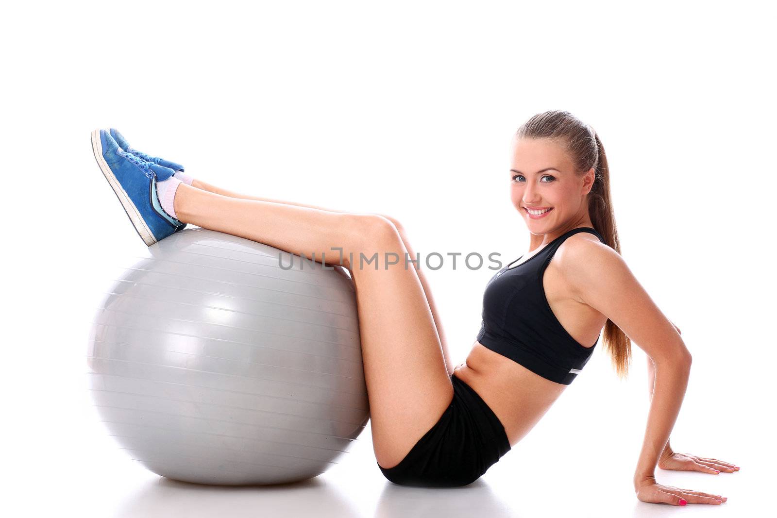 Beautiful and smiling woman doing abs exercises with fitness ball over white background