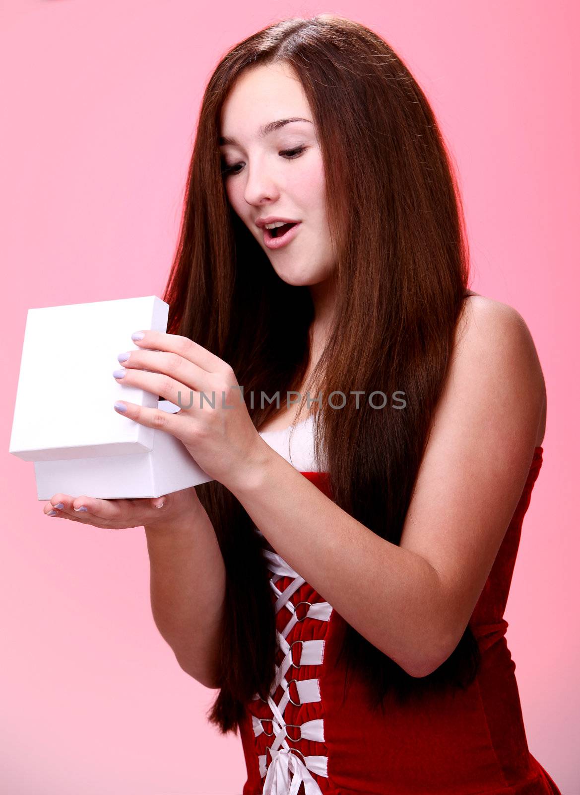 Portrait of young and beautiful christmas girl in red opening a gift