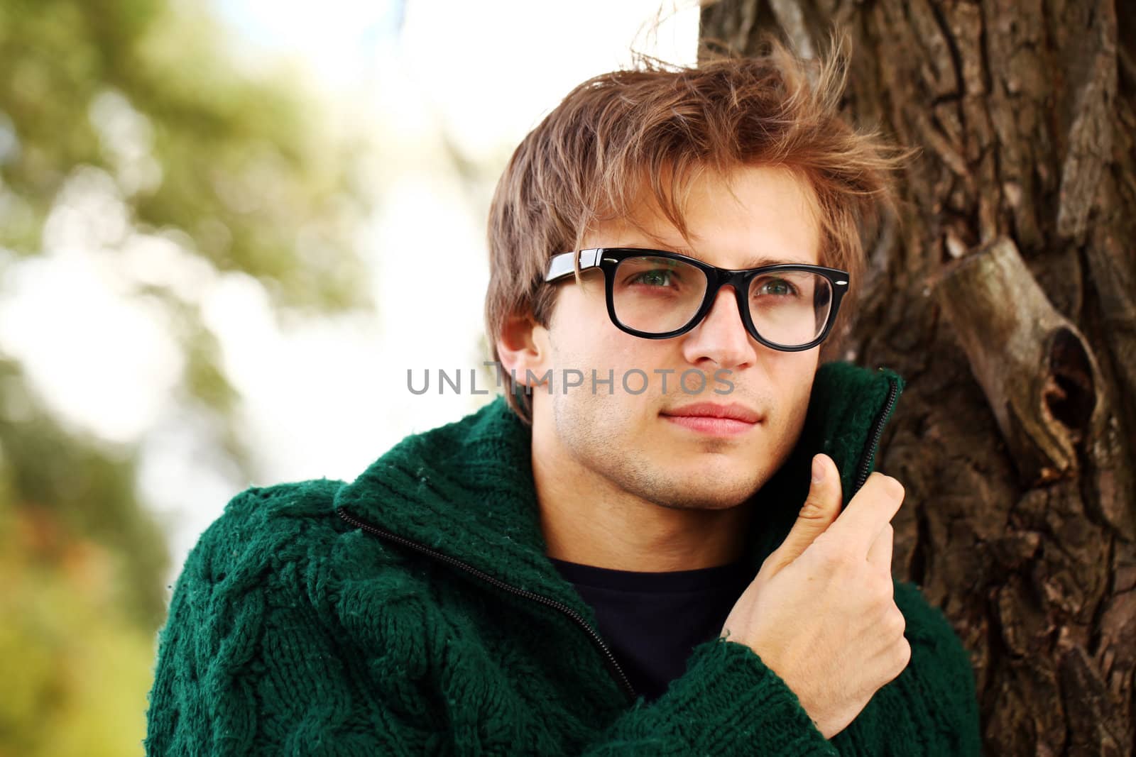 Potrait of handsome and smart guy at cold autumn day in the park