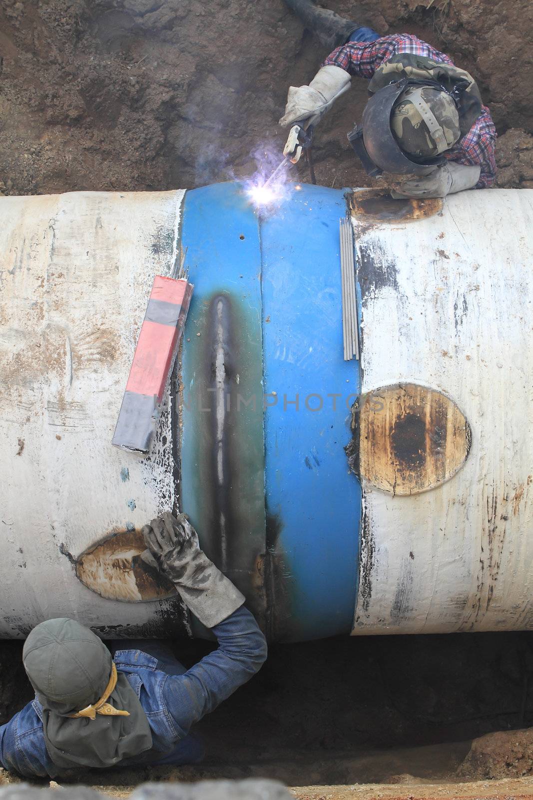 Male welder worker wearing protective clothing fixing welding    by rufous