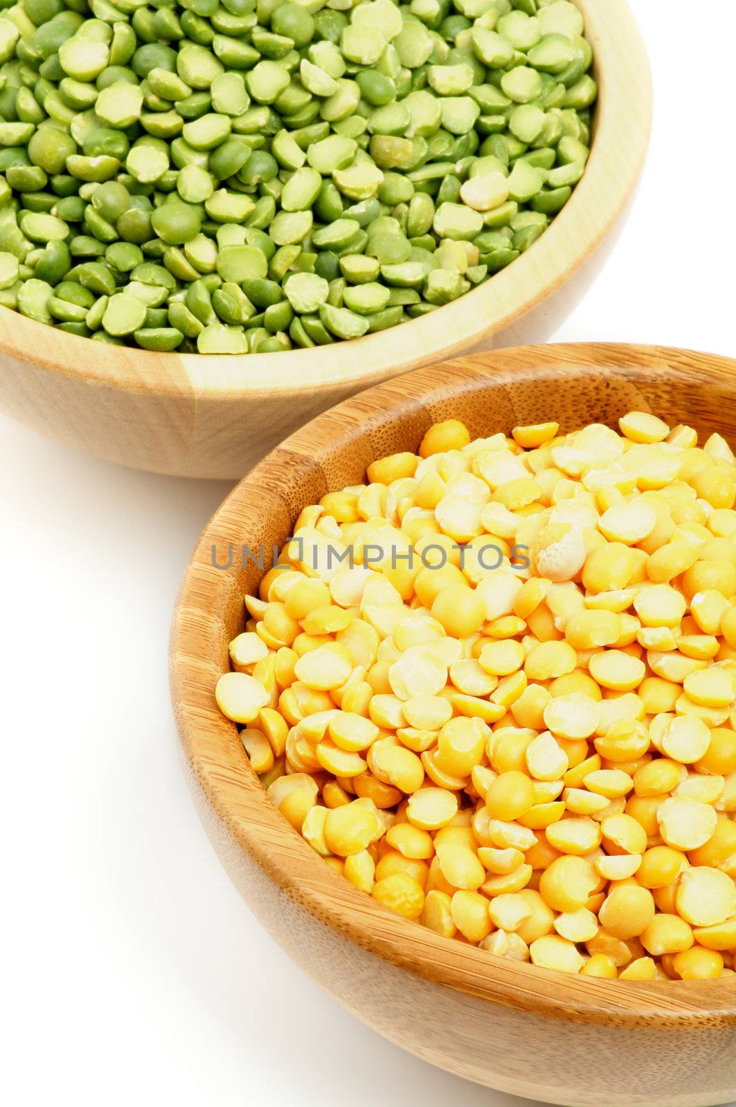 Two Wooden Bowls with Yellow and Green Split Peas in closeup on white background
