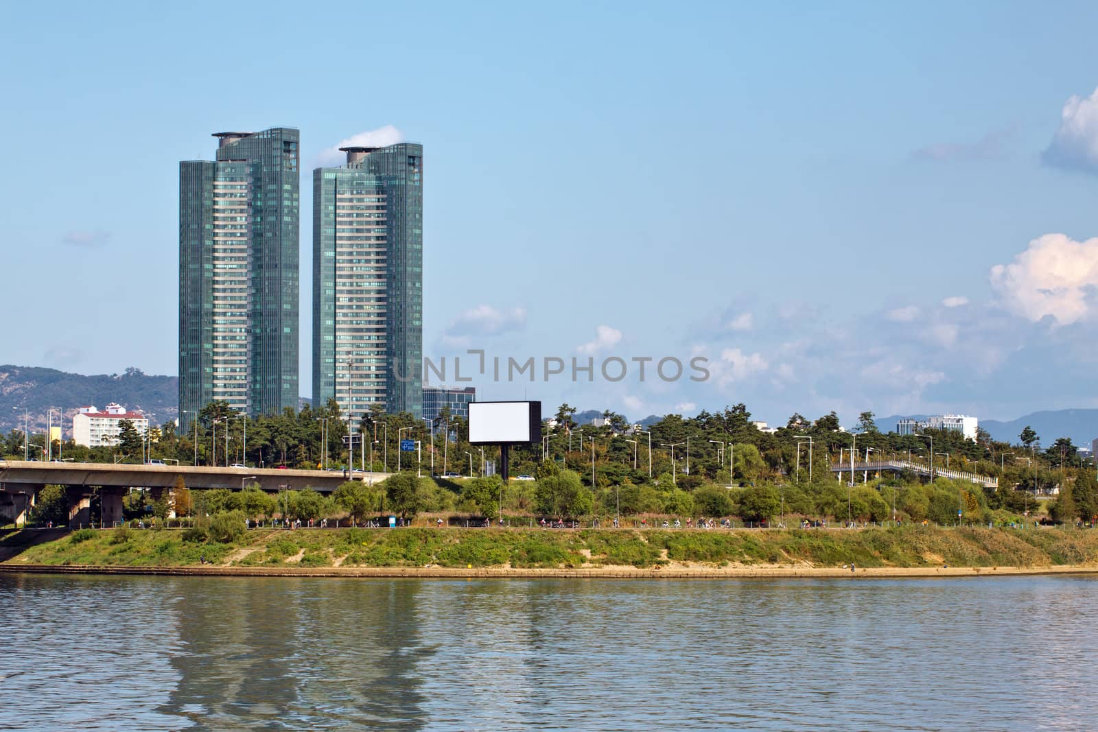 Two modern buildings and green park over river