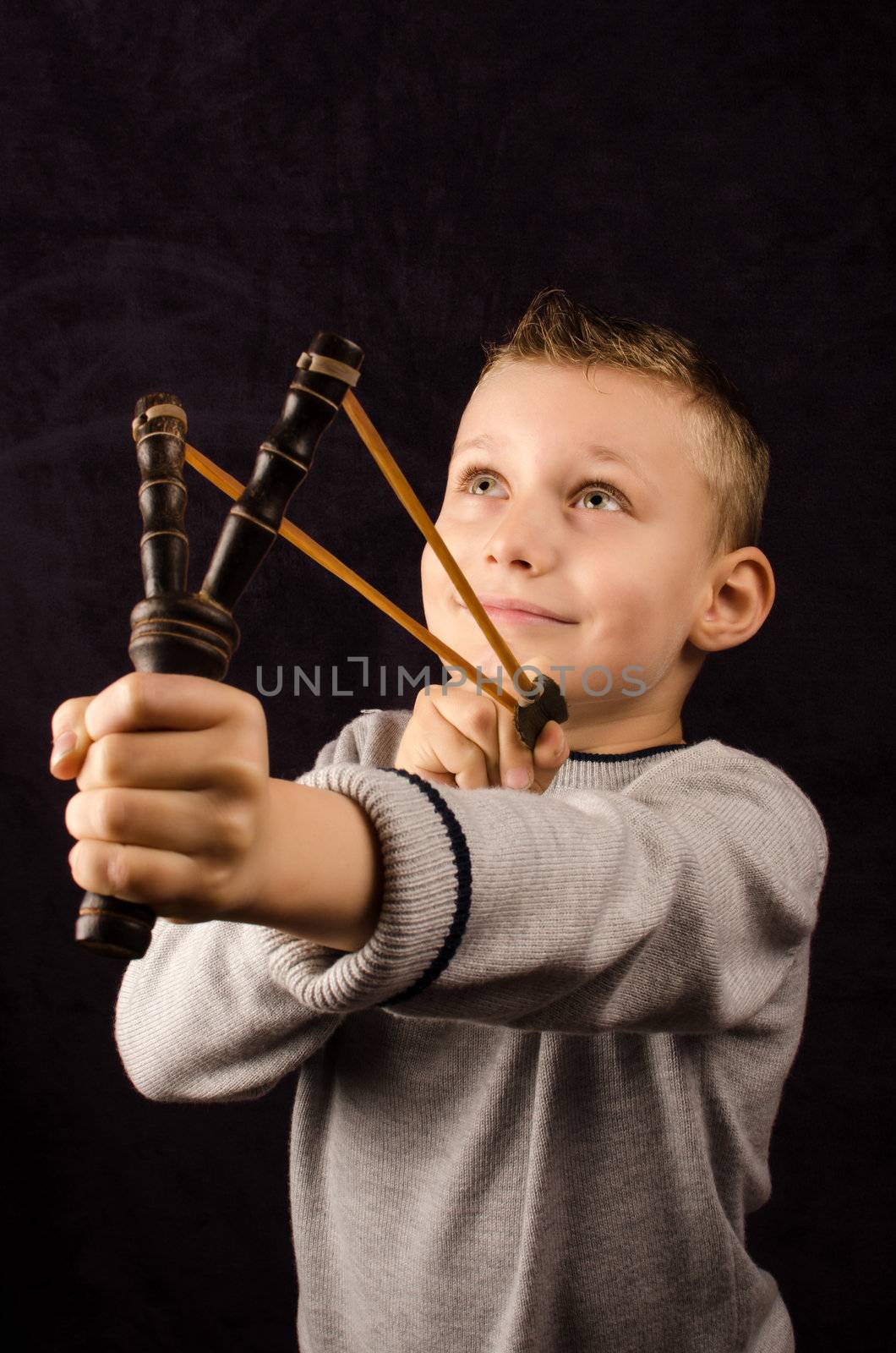 Studio photo of a young boy with slingshot