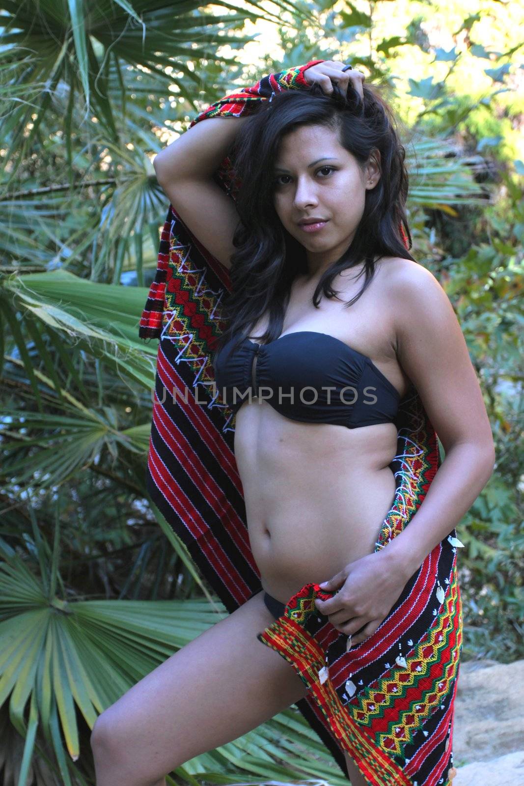 Model shot of a Hispanic beauty in front of a palm tree.