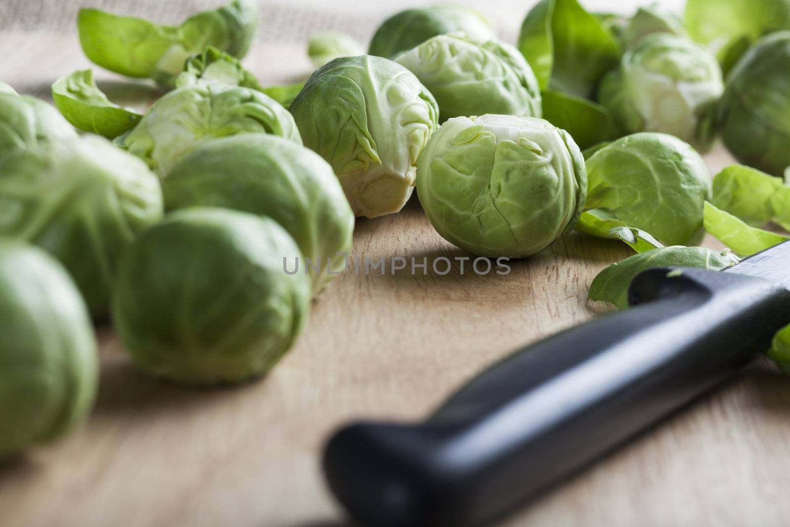 Burssel sprouts on cutting board with a knife.