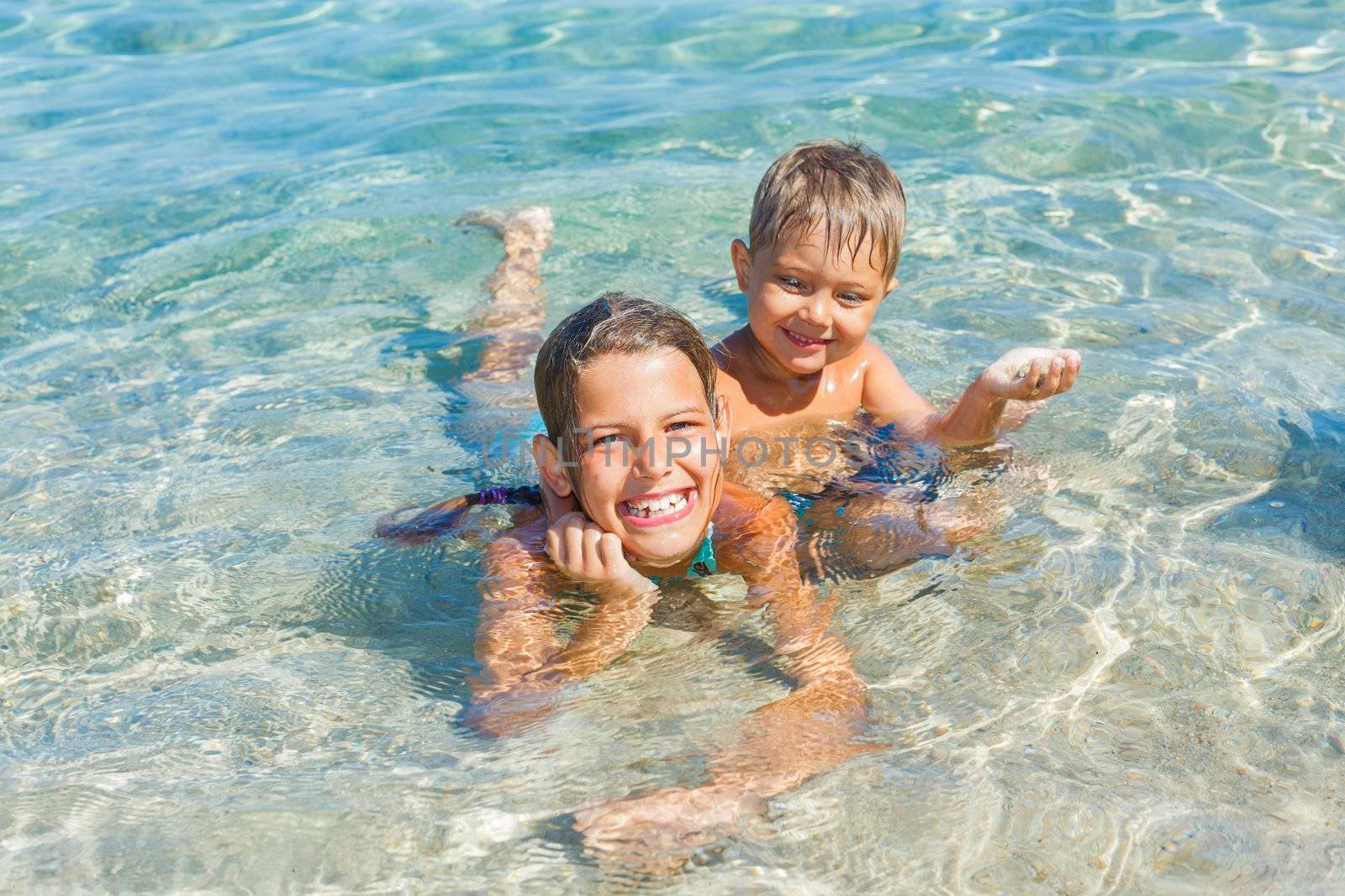 Happy kids. Sister and brother playing and swimming in the transparent sea