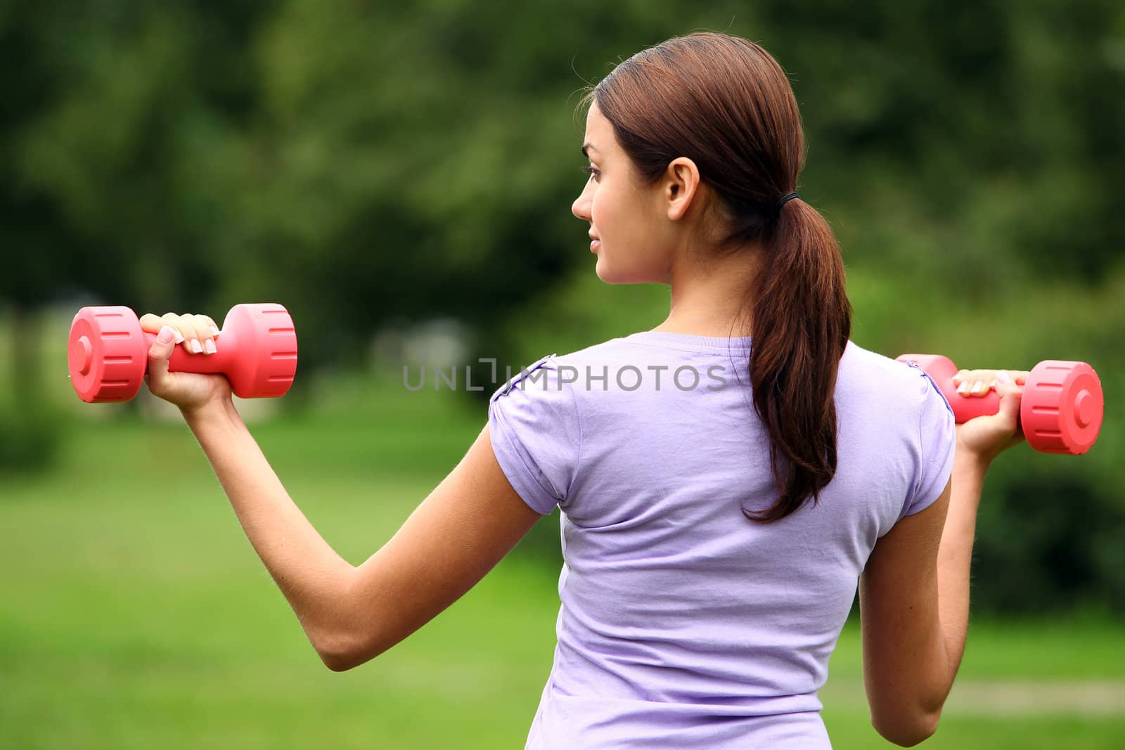 Woman doing exercises with dumbbells in the park by rufatjumali