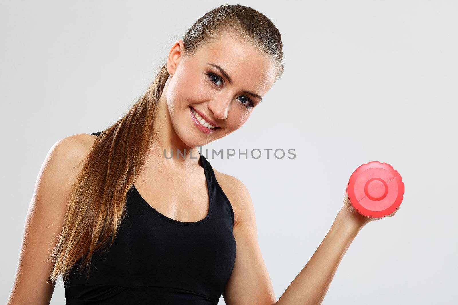 Beautiful brunette working out with dumbbells over gray background