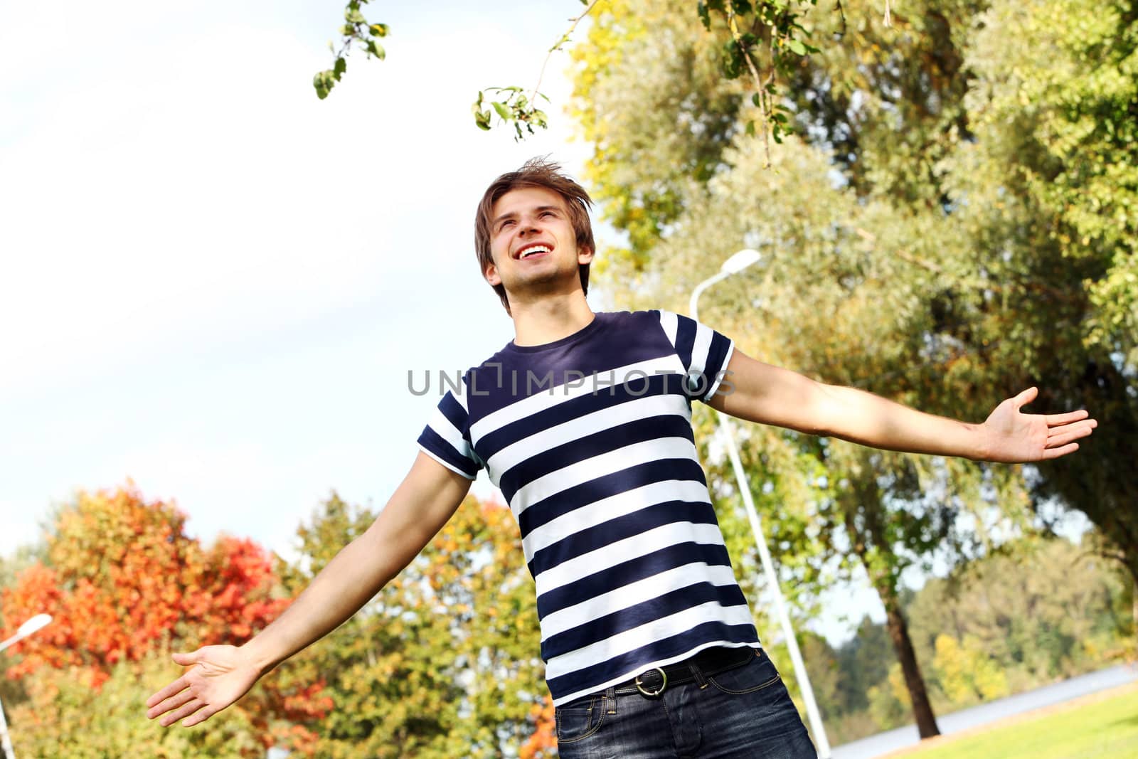 Portrait of happy and attractive young man at warm day in autumn park