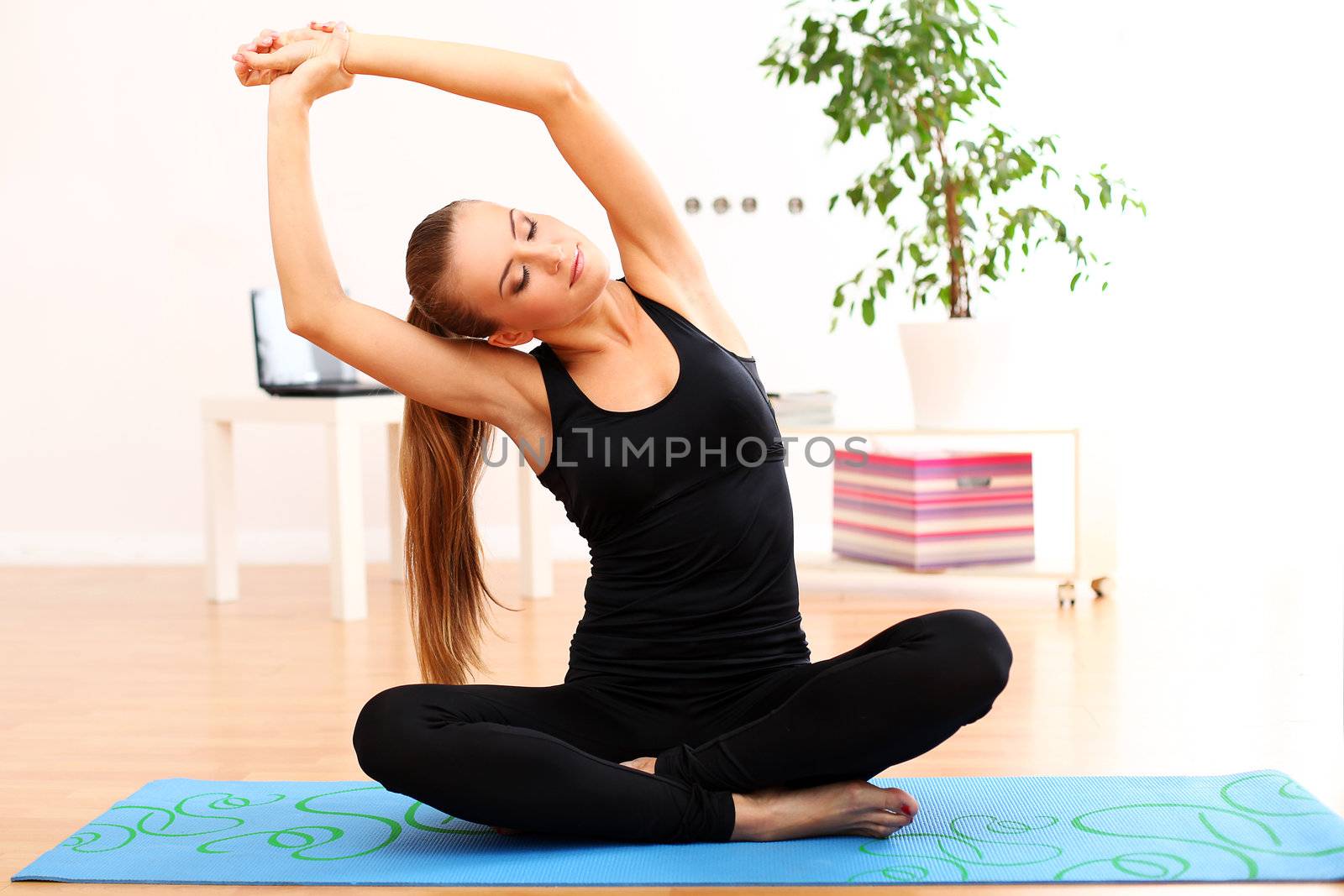 Young and beautiful woman do yoga exercises at home on blue mat