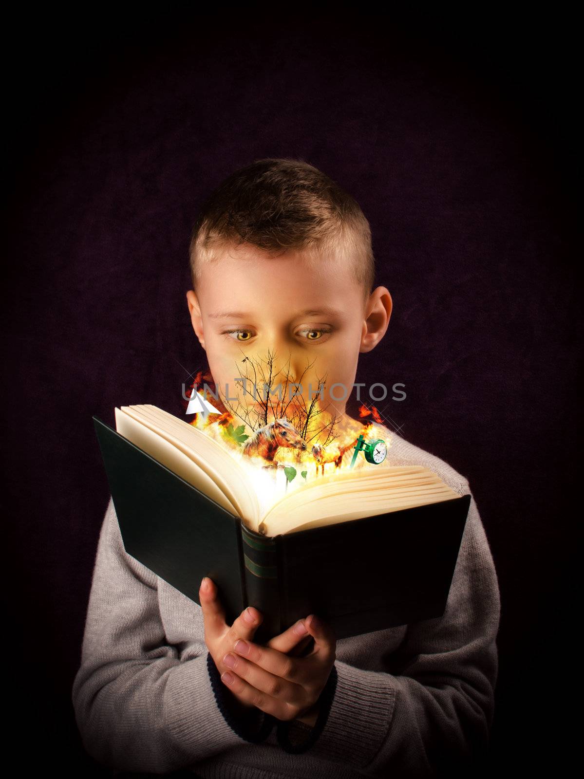 Young boy reading and looking at a magic book