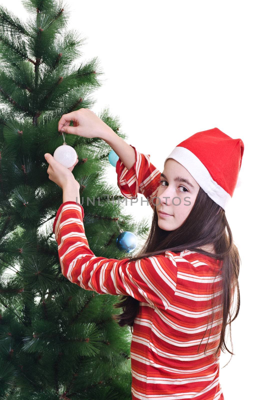 Young girl wearing beanie decorating christmas tree, eye contact, vertical shot