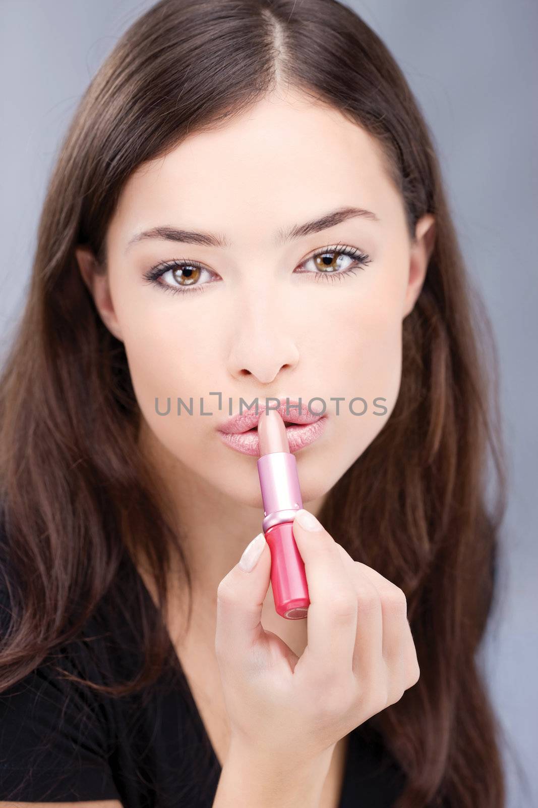 Pretty girl putting lipstick on her lips, focus on lips