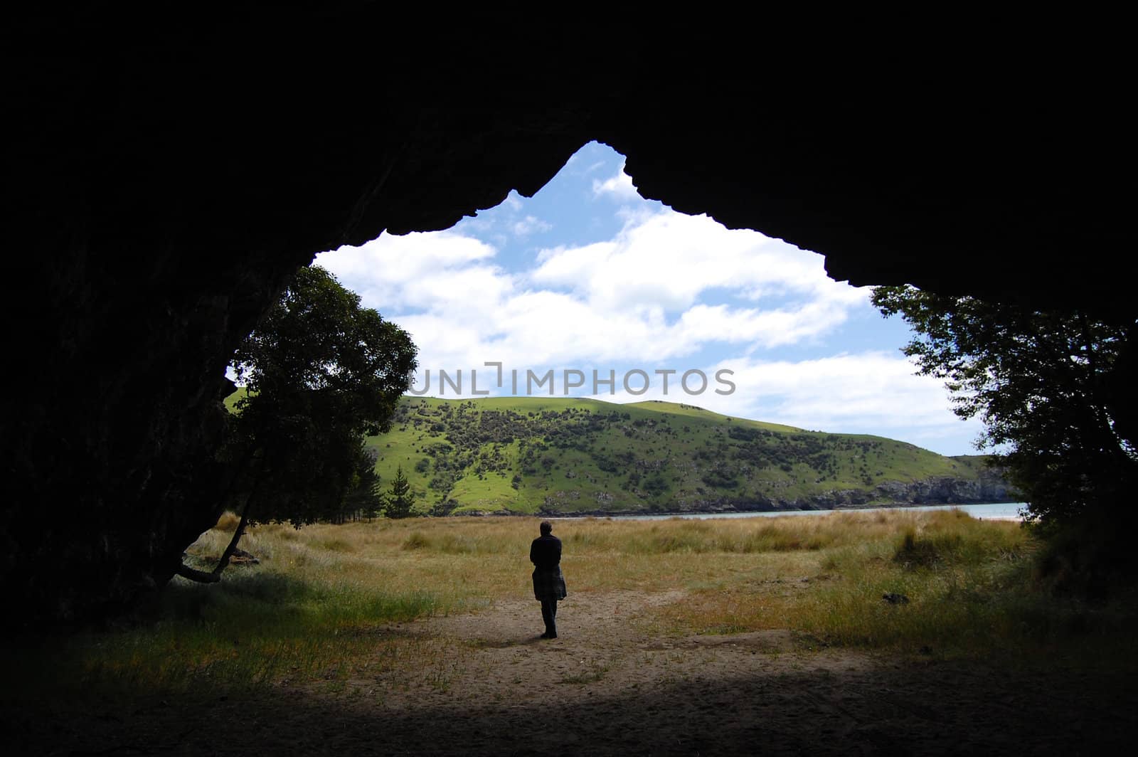 Man in front cave entrance, Okains Bay, Banks Peninsula, New Zealand