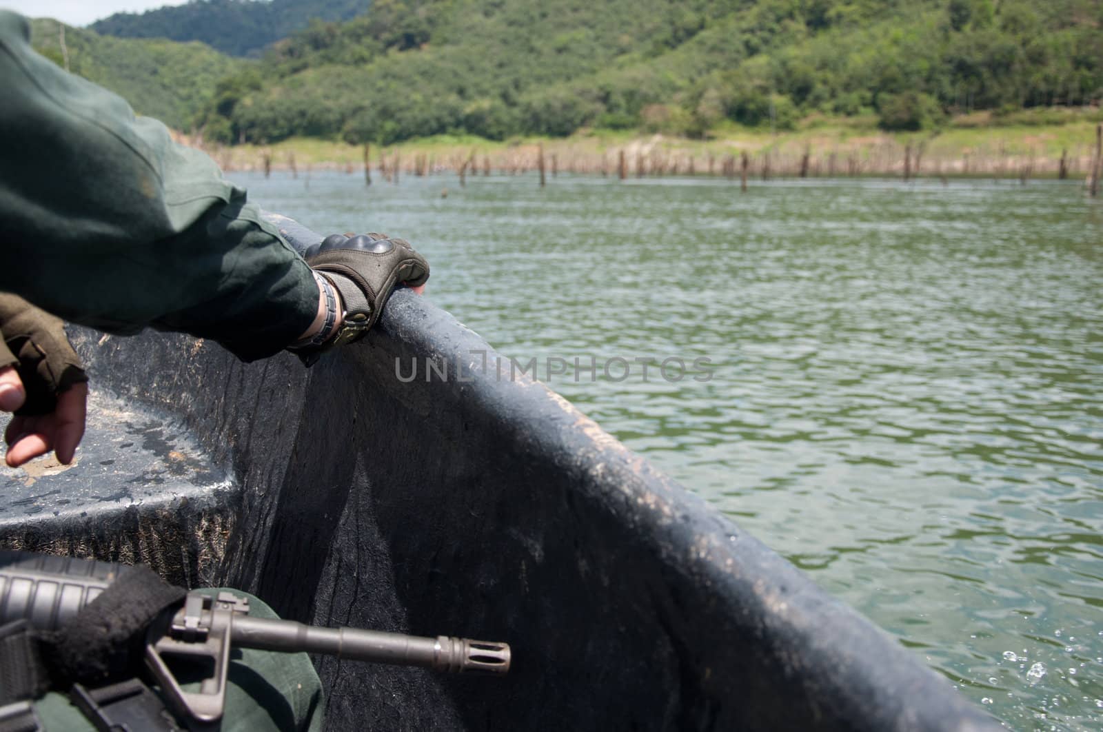 hand of a soldier on running ship with gun beside