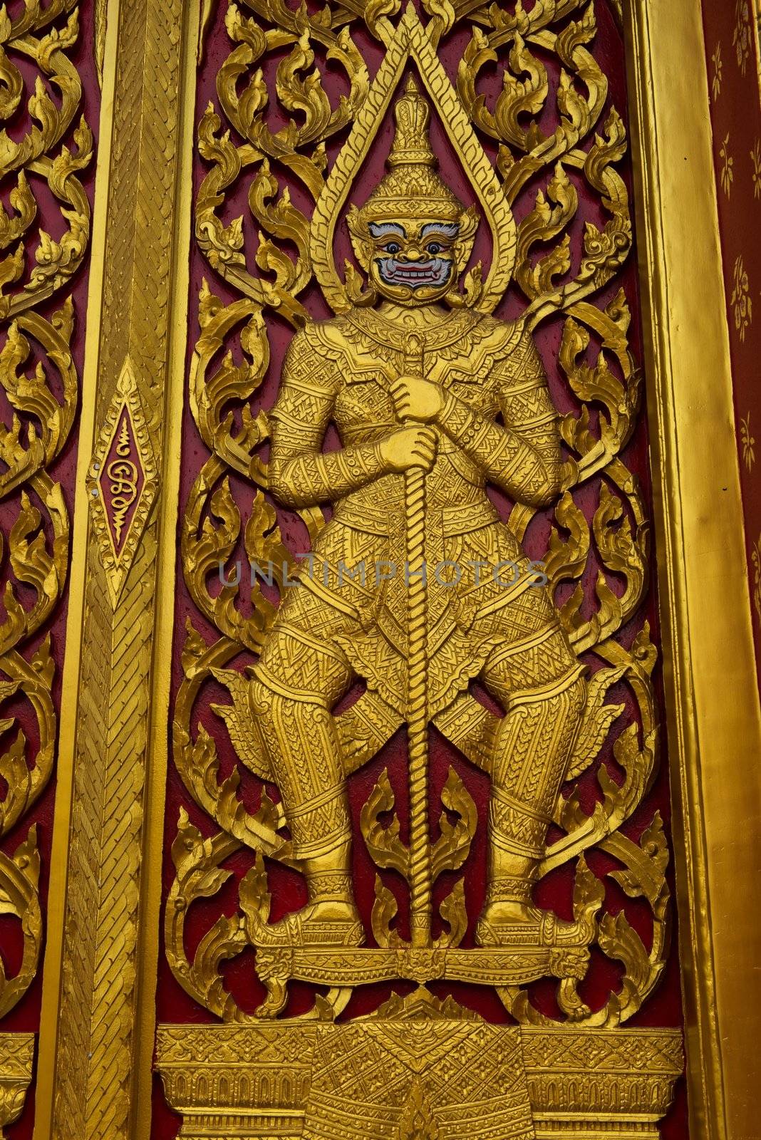 Golden temple gate with guarding demons in Bangkok, Thailand