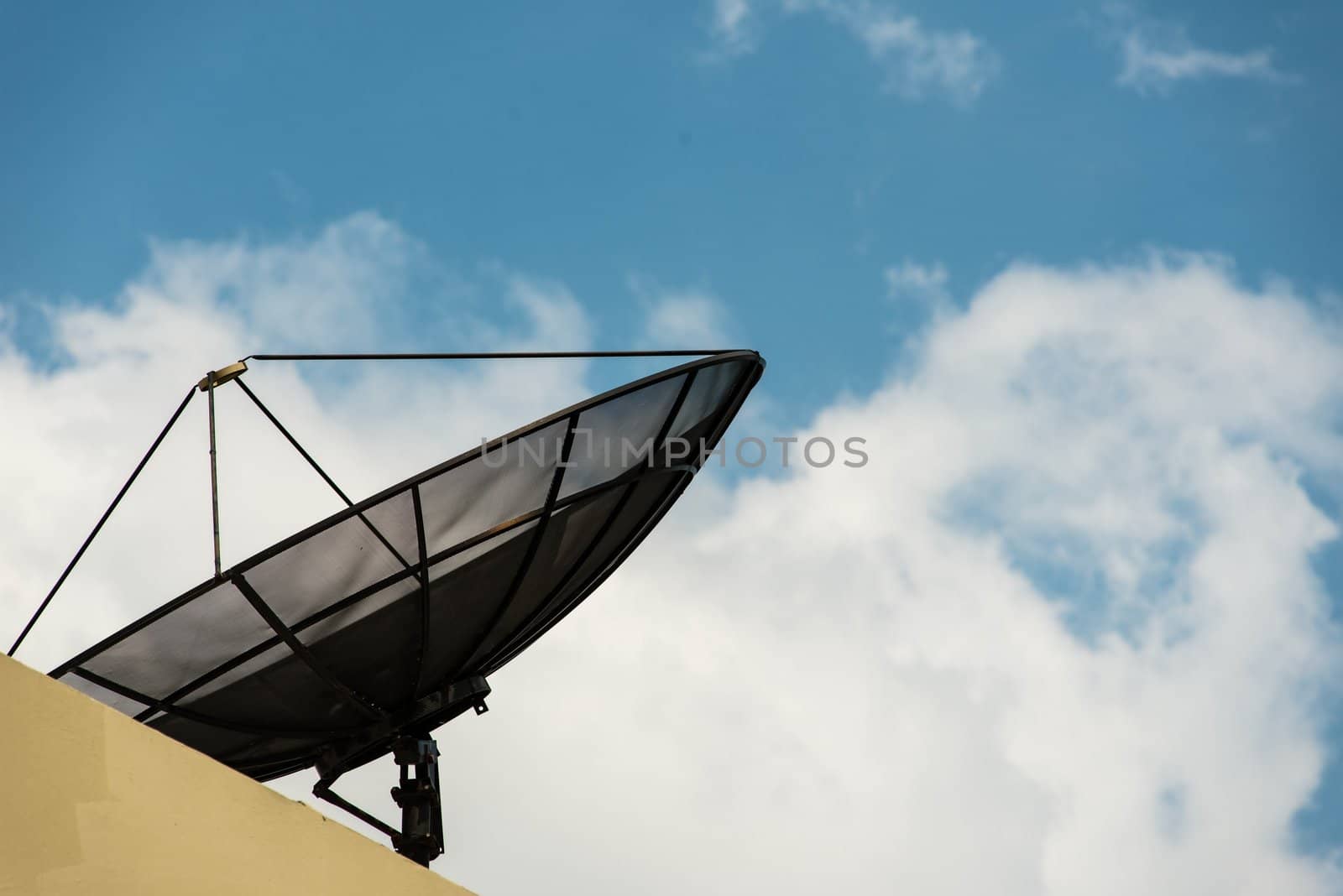 Black cable television satellite dish on the roof with blue sky