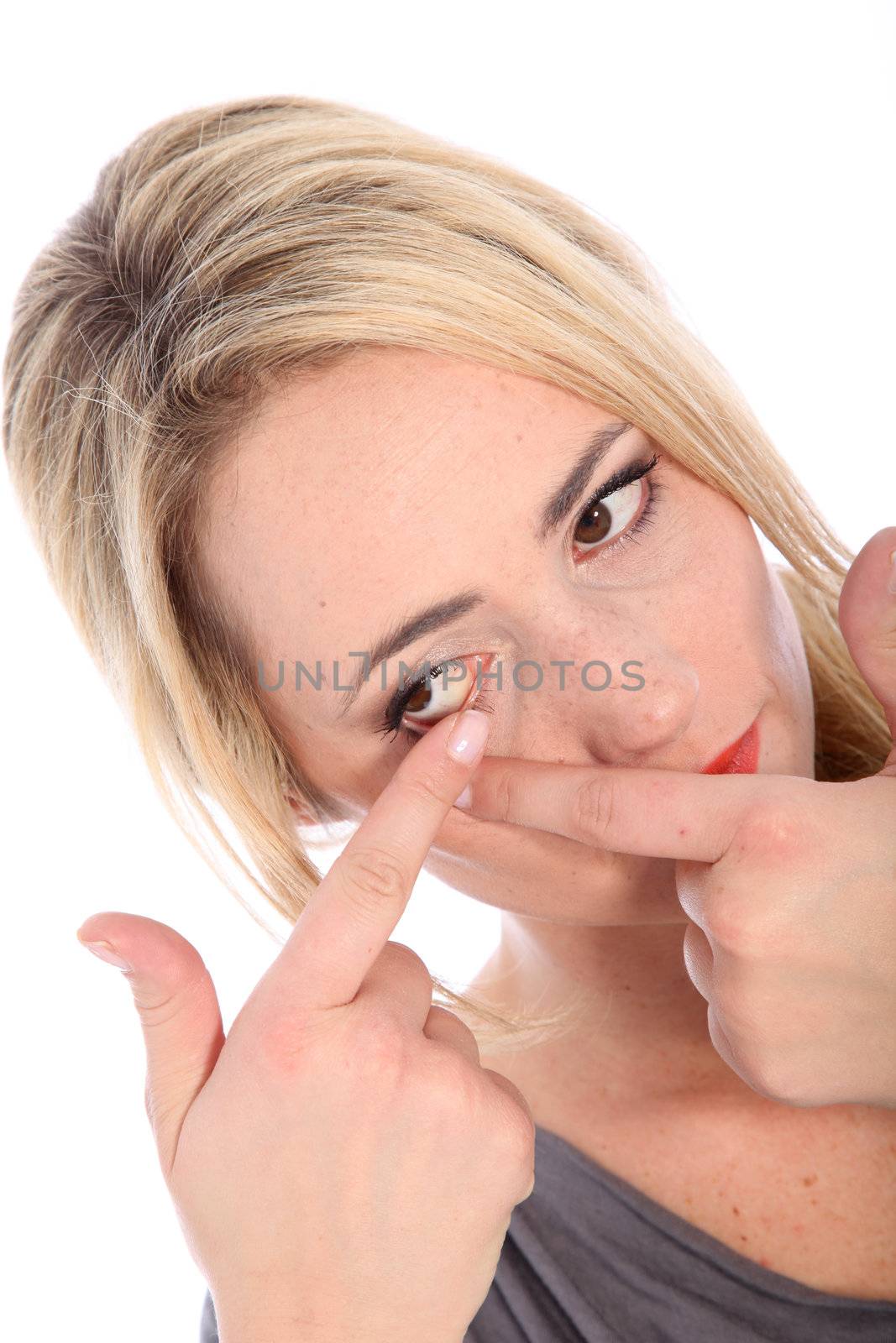 Closeup portrait of beautiful young blonde woman putting in contact lenses