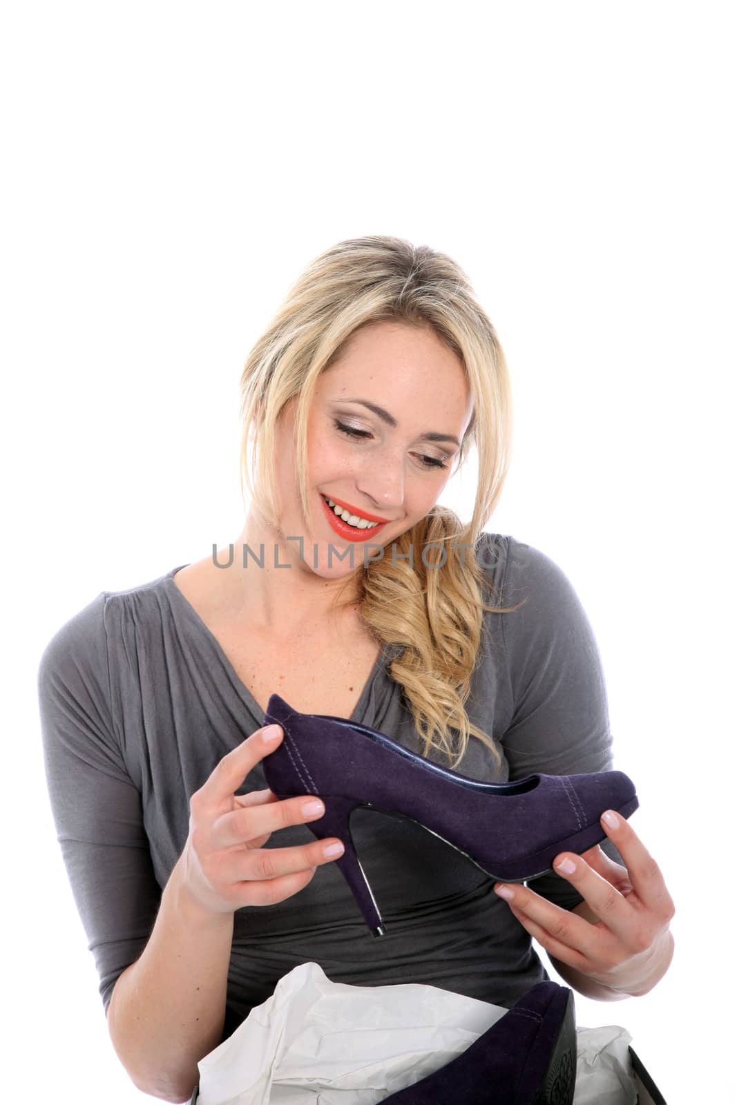 Happy young blonde woman holding purple high heel in both hands isolated on white