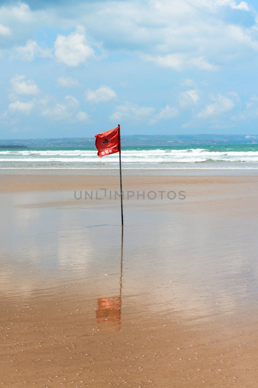 Red flag on beach with no swimming notes. Season of storms and strong currents.