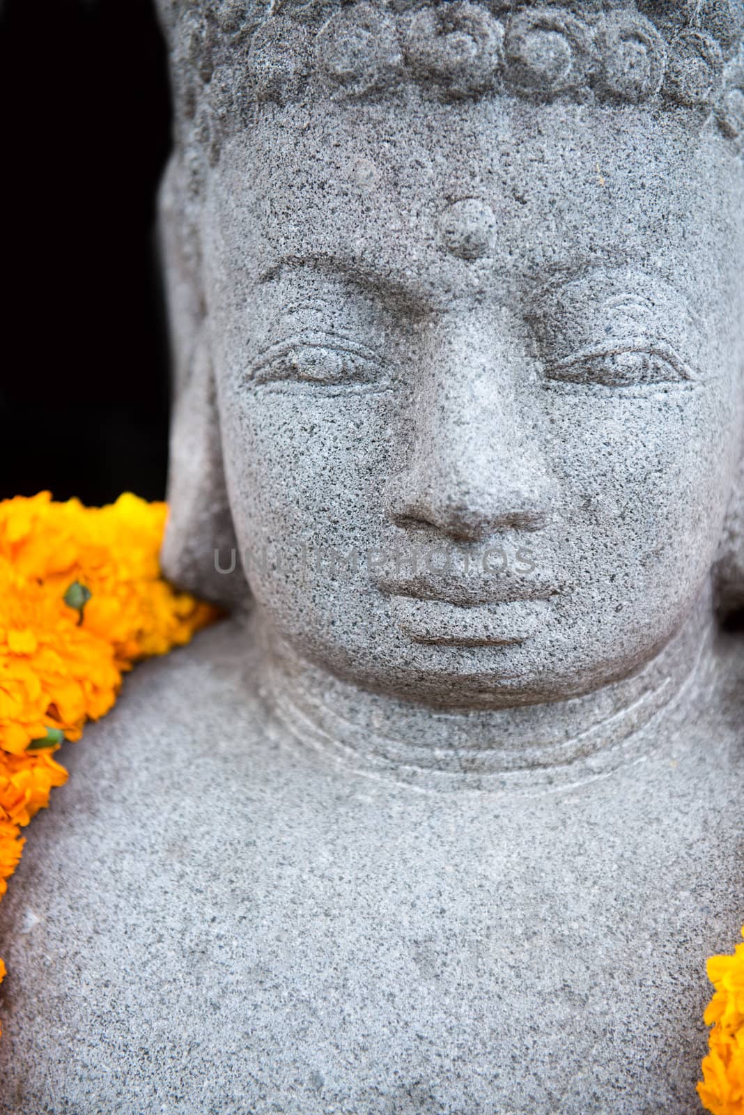 Stone Buddha statue with yellow flowers