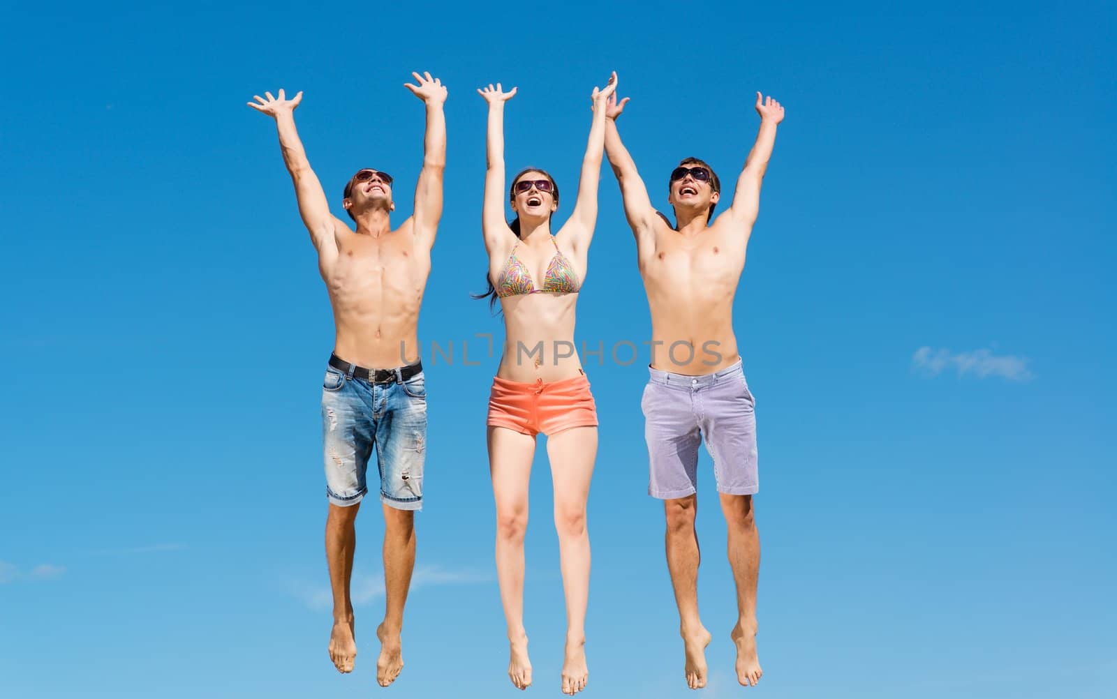 a group of young friends jumping on a background of blue sky, having fun