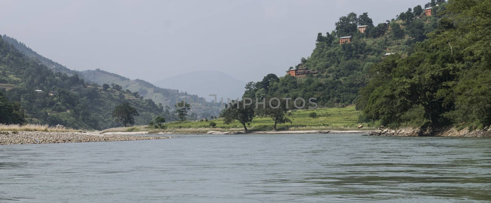 river in sun koshi, nepal with forest and small buildings