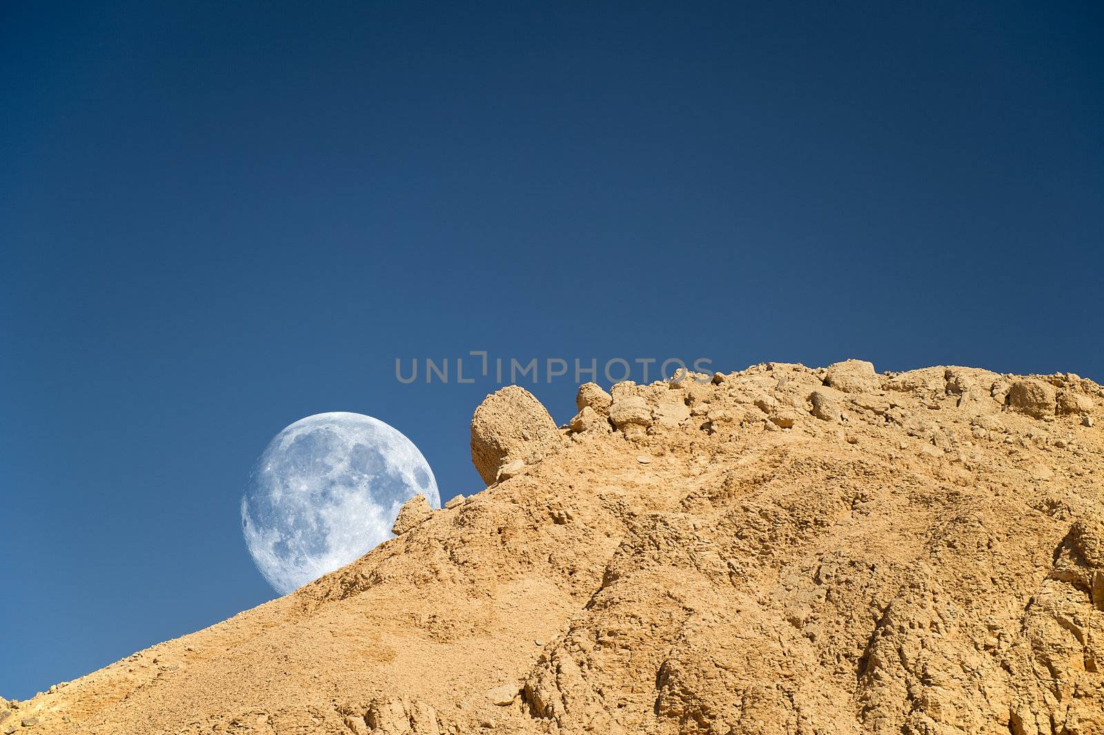 Full moon setting over the rocky desert in Egypt