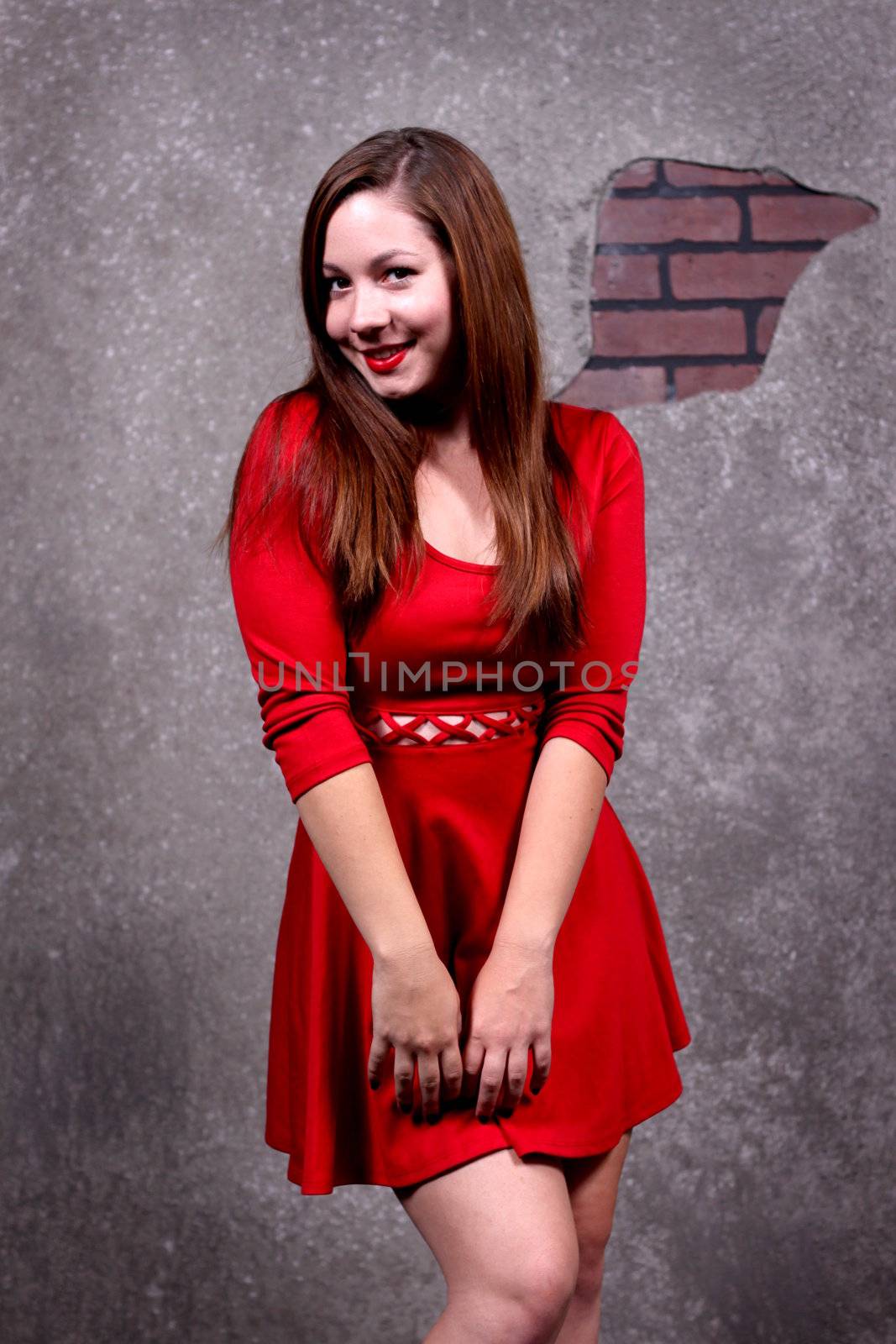 Woman in a red dress in front of a concrete wall.