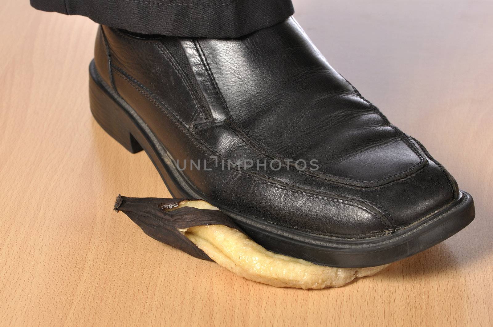 Closeup of man's black shoe stepping on over ripe banana